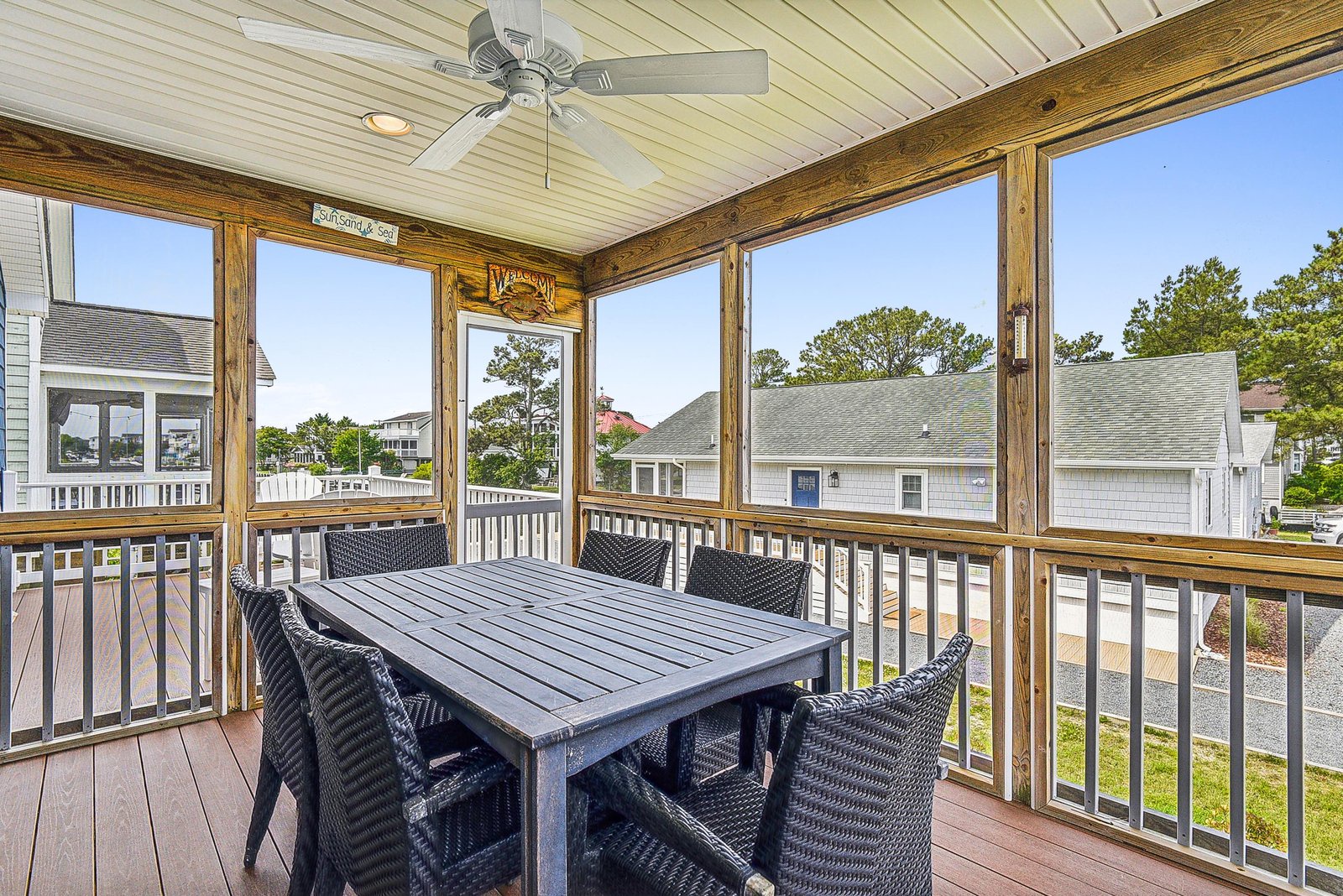 Enjoy your morning coffee or al fresco dining at this screened porch with ceiling fan, where large windows bring in natural light and neighborhood views while keeping you comfortable.