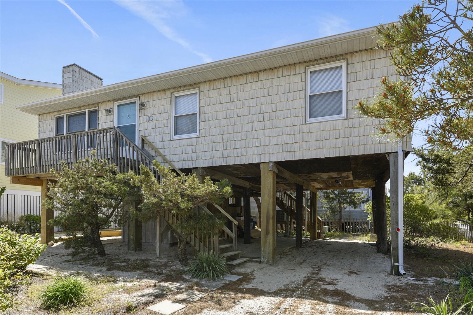 A coastal retreat elevated on sturdy pilings, surrounded by natural greenery. The ground-level parking and beachside setting offer both convenience and a true seaside escape.