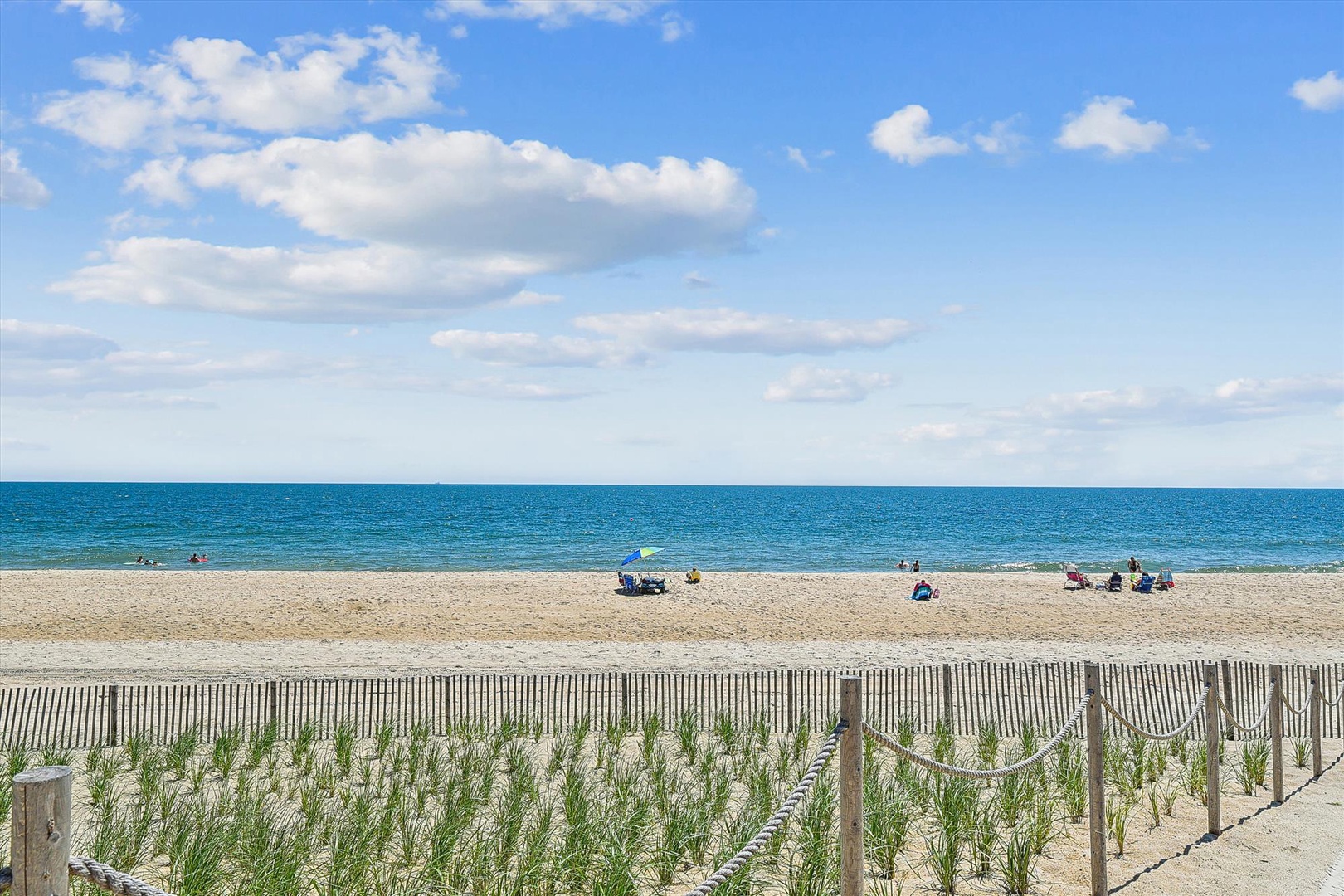 A pristine sandy beach meets turquoise waters under blue skies, offering an idyllic coastal escape just steps from the property. Perfect for sunbathing, swimming, or strolling along the shore.