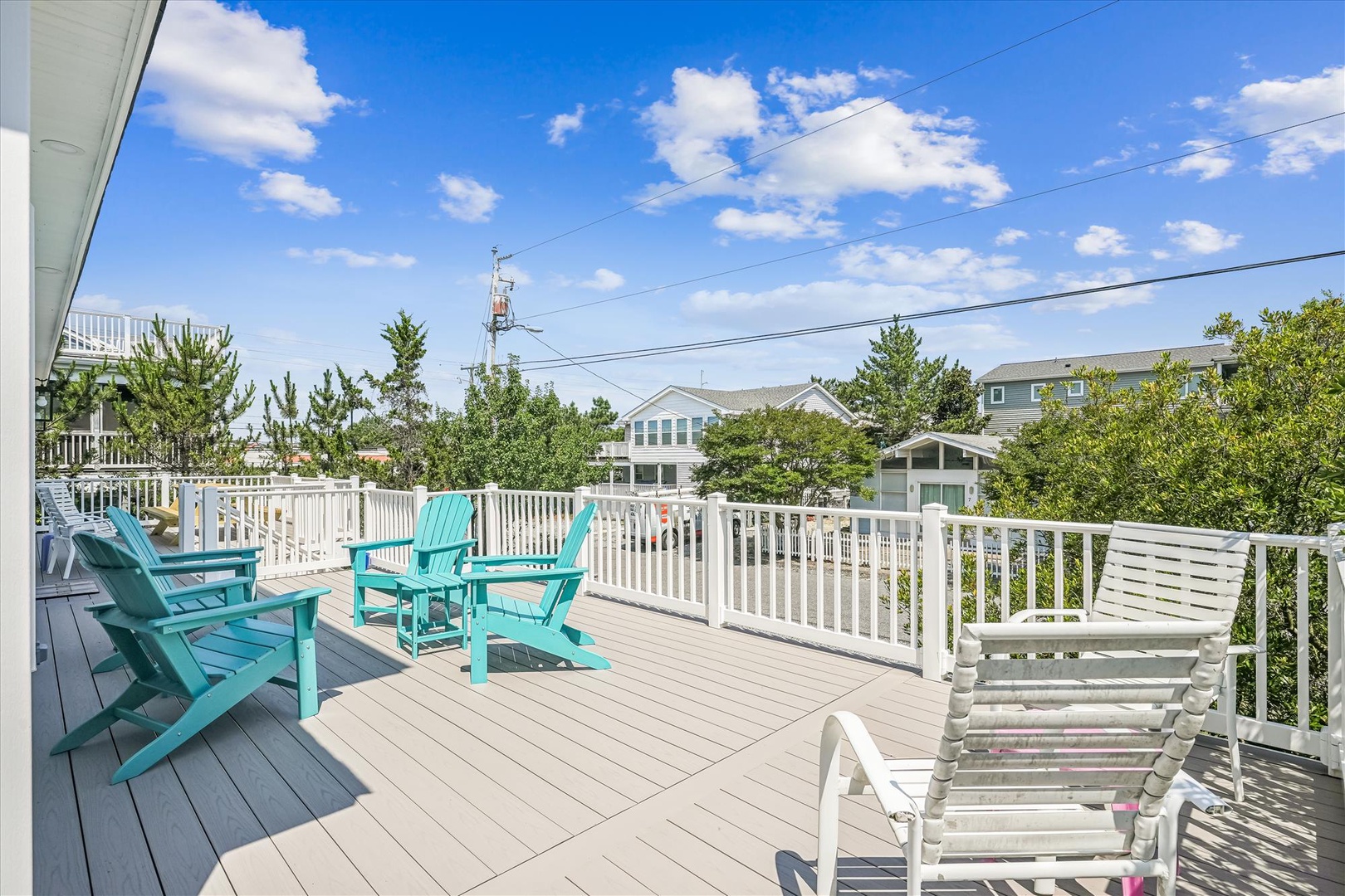 Relax on your private deck with turquoise Adirondack chairs, where sunny skies and coastal charm create the perfect retreat.