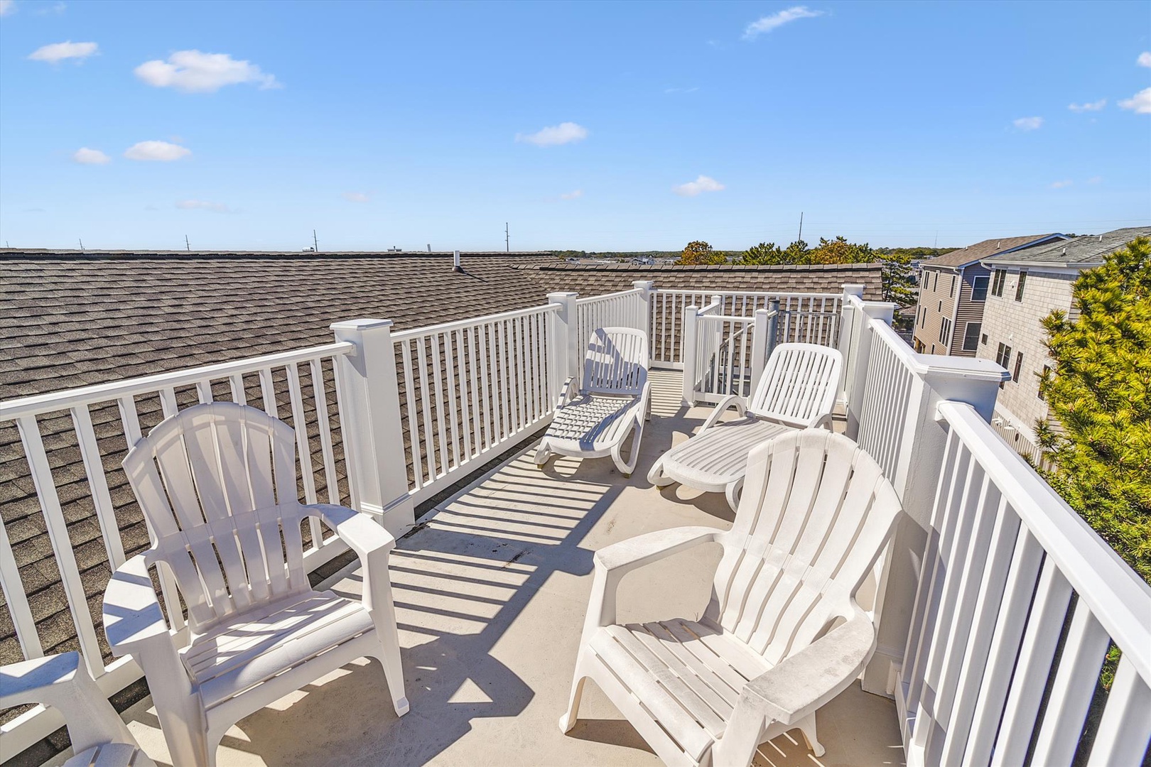 This rooftop deck features classic Adirondack chairs and bright coastal skies, offering a peaceful open-air retreat just steps from your vacation space.