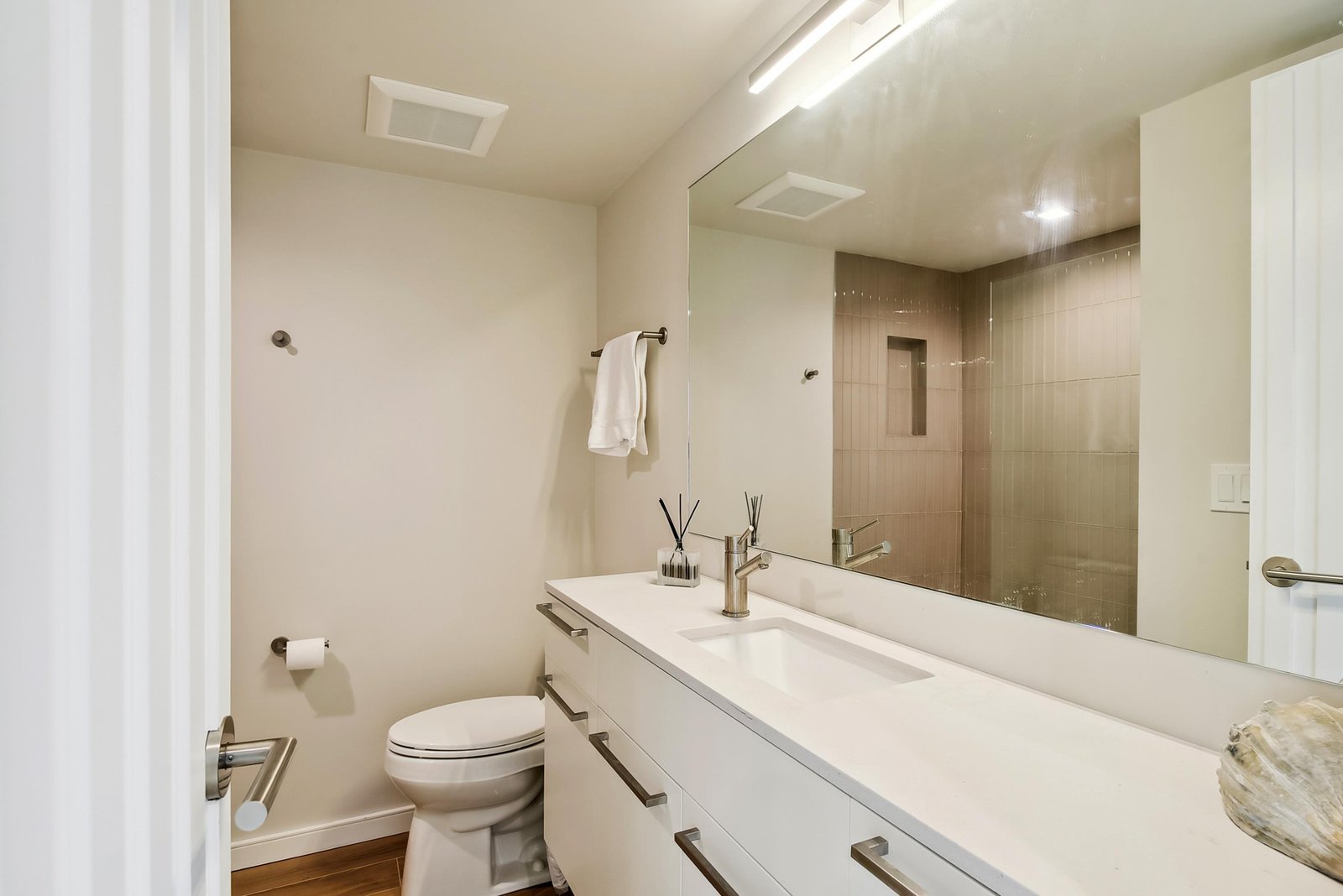 Step into your sleek, modern bathroom with a spacious vanity, generous mirror, and walk-in shower. Fresh towels and thoughtful details await you.