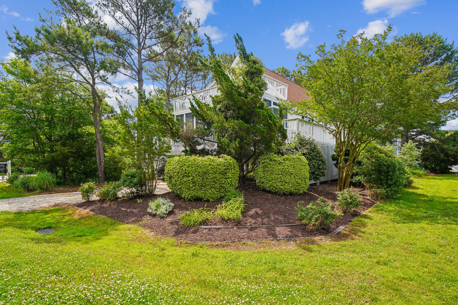 Mature trees and thoughtfully landscaped gardens frame the property's exterior, creating a peaceful, green setting beneath clear blue skies.