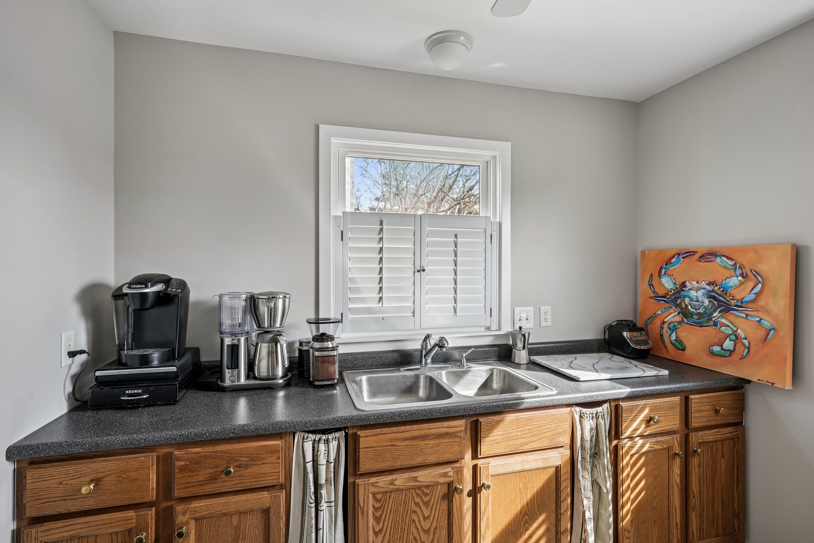 Your cozy kitchenette features everything you need - coffee maker, sink, and charming coastal artwork to start your mornings right.