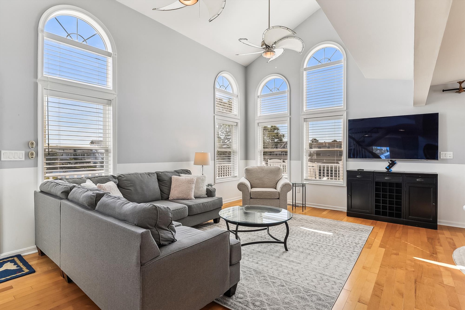 Unwind in your bright, airy living room with soaring ceilings, elegant arched windows, and cozy seating—your perfect home base for relaxation and entertainment.