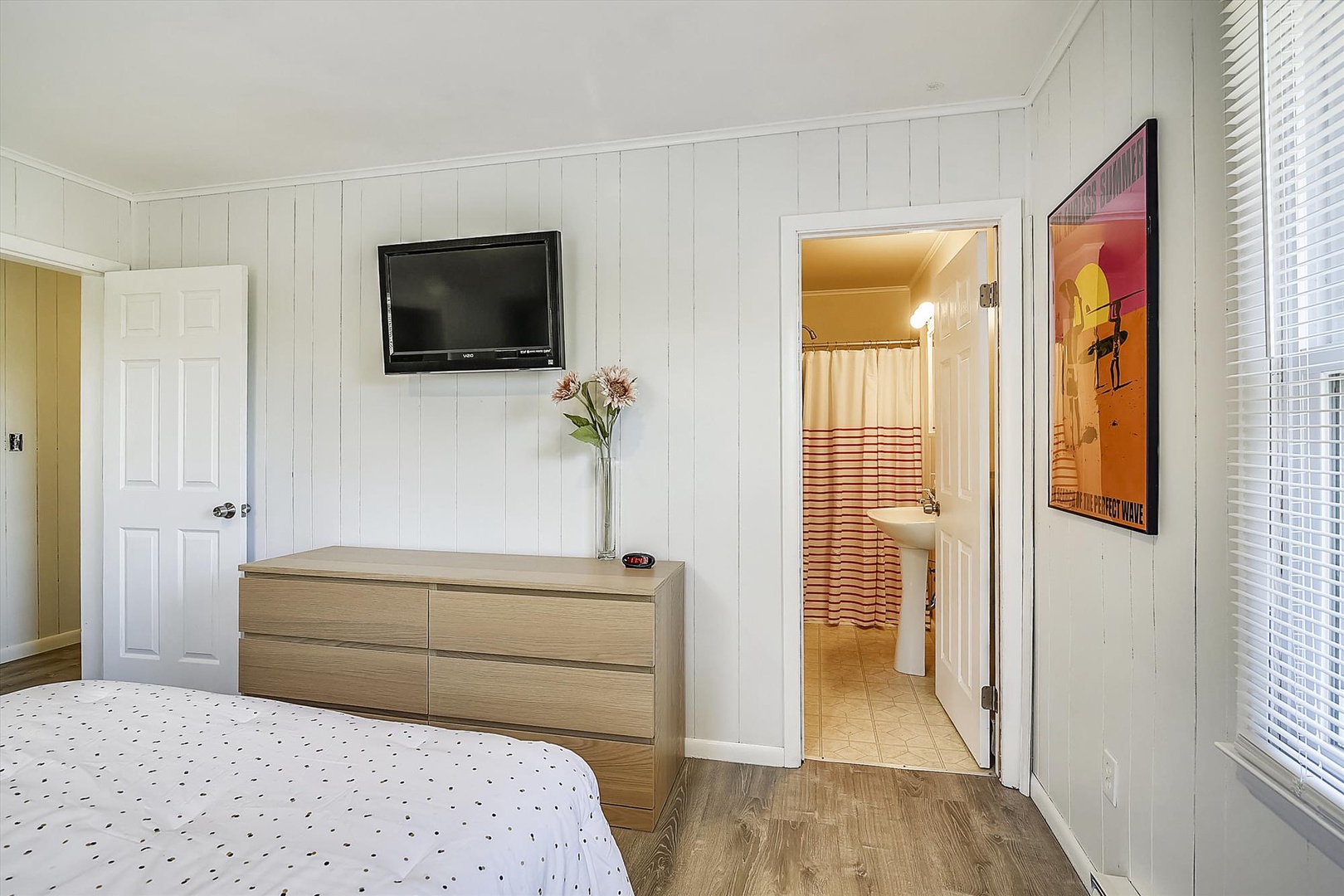 Your bright, peaceful bedroom features a cozy bed, smart entertainment setup, and a private en-suite bathroom just steps away.