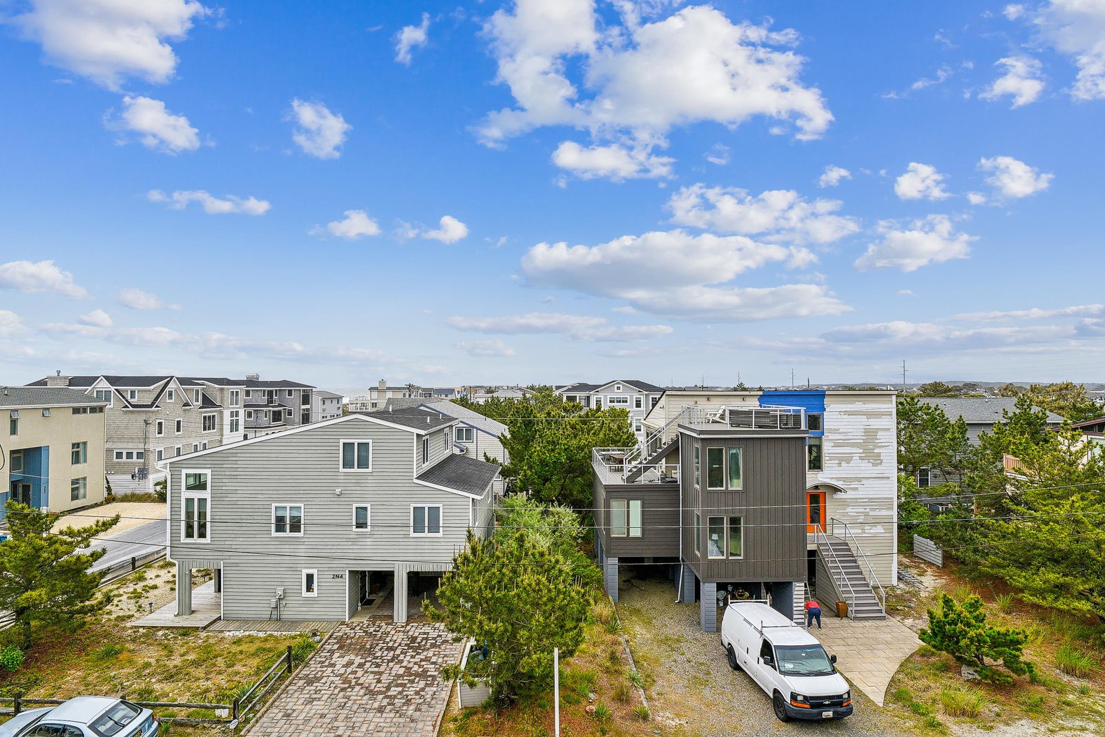 An elevated beachside neighborhood with contemporary vacation homes amid natural dunes and greenery, close to coastal amenities and the shore.