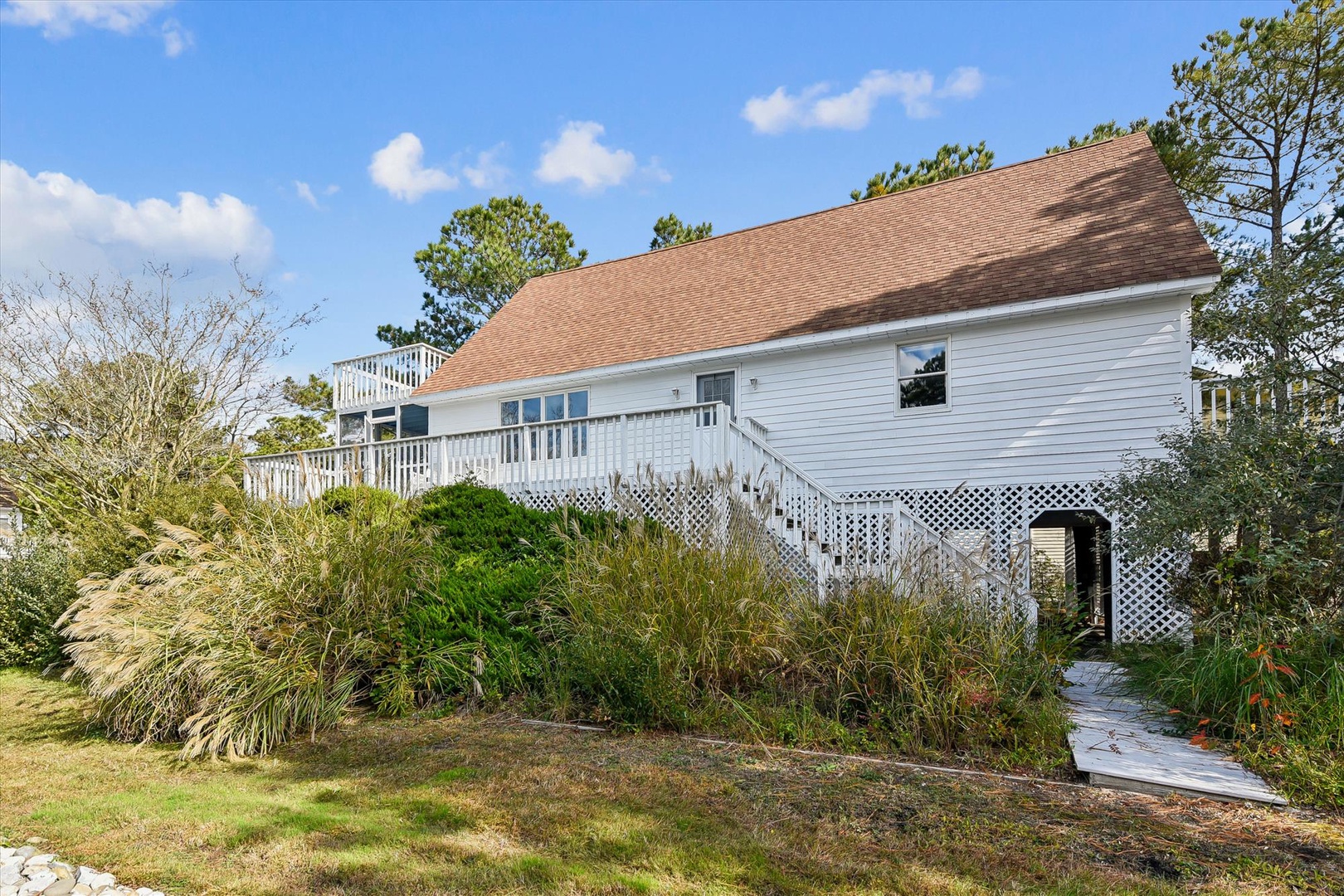 Charming elevated cottage with spacious deck and natural landscaping in a peaceful wooded setting.