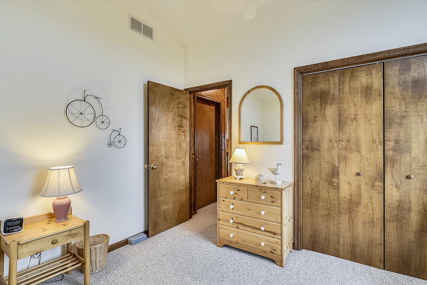 Settle into your cozy bedroom with rustic wood furnishings, soft carpet underfoot, and charming touches like vintage bicycle wall art. A peaceful retreat with ample storage and natural warmth.