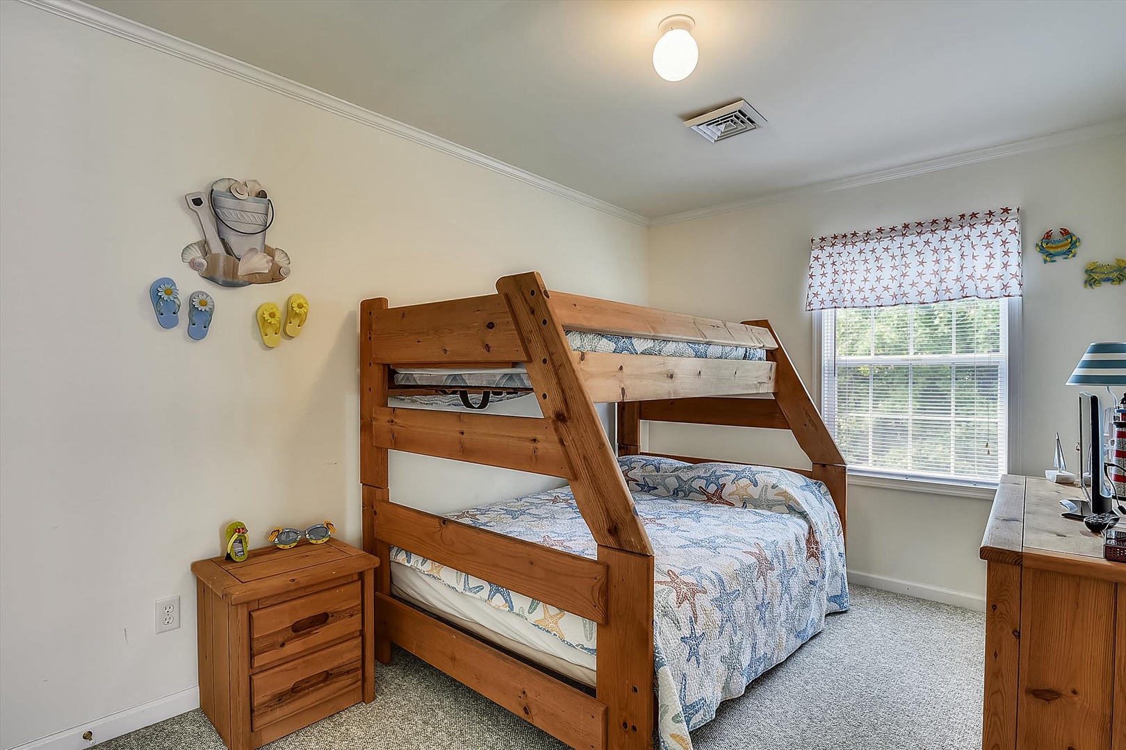Your kids will love this cozy bunk room with sturdy wooden beds, playful beach-themed decor, and bright natural light streaming through the window—perfect for creating vacation memories together.
