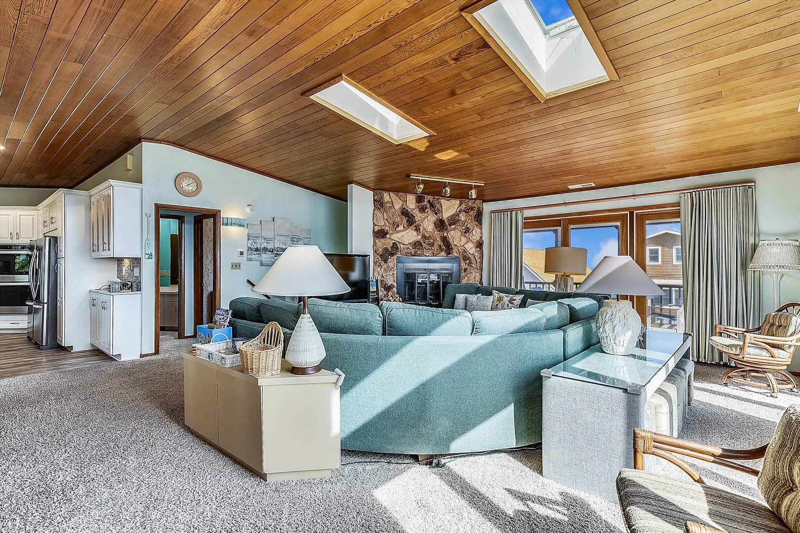 Picture yourself unwinding on these plush sofas under the warm glow of skylights, while the cozy stone fireplace creates the perfect ambiance for your seaside getaway.