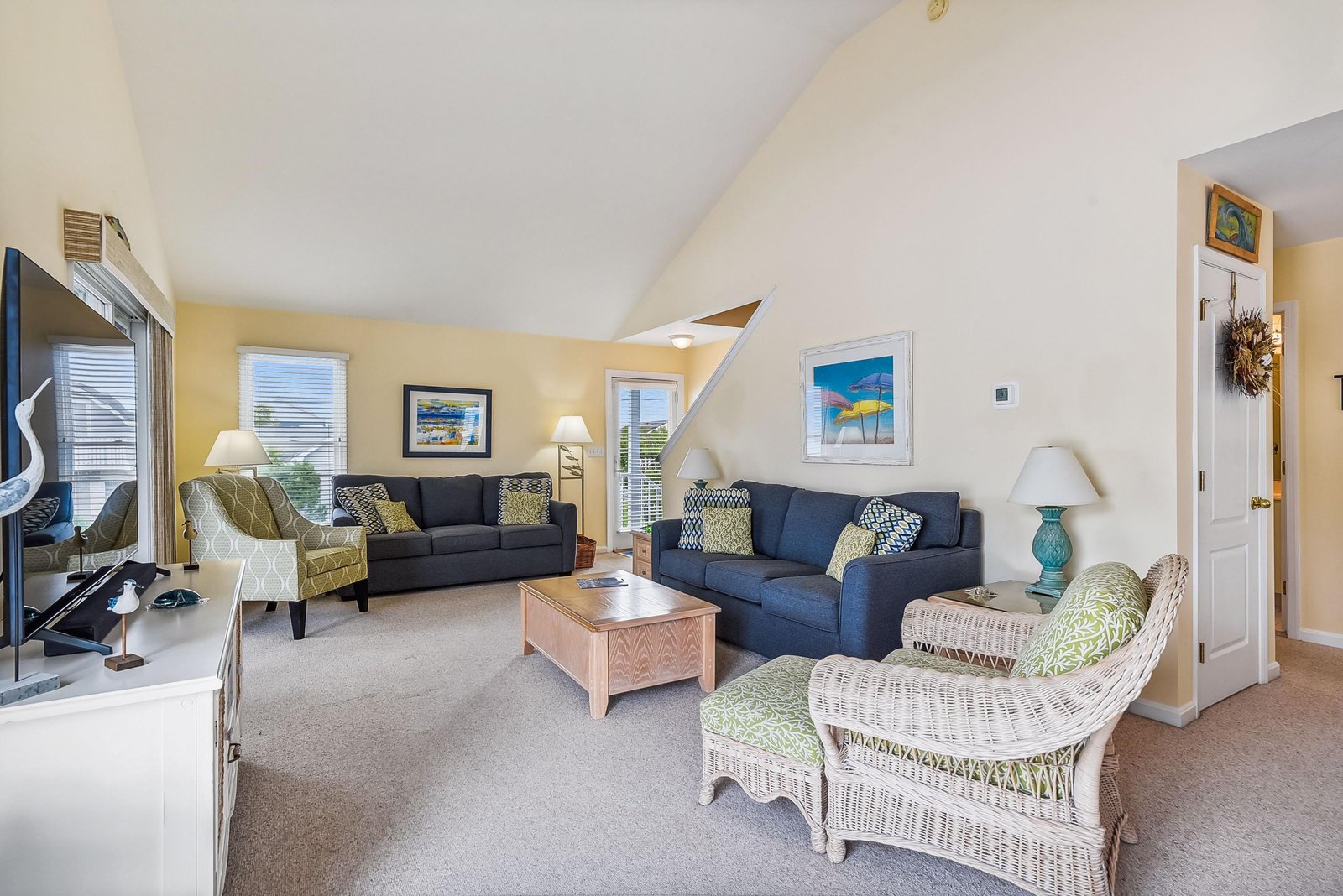 Settle into your spacious living room with soaring vaulted ceilings, plush seating for everyone, and coastal charm that invites you to unwind.