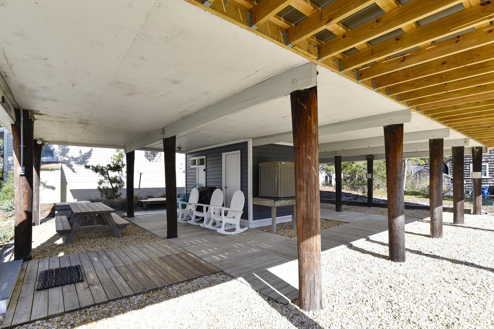 Covered outdoor area beneath the property with rustic wooden pillars, picnic seating, and rocking chairs for relaxing between adventures.