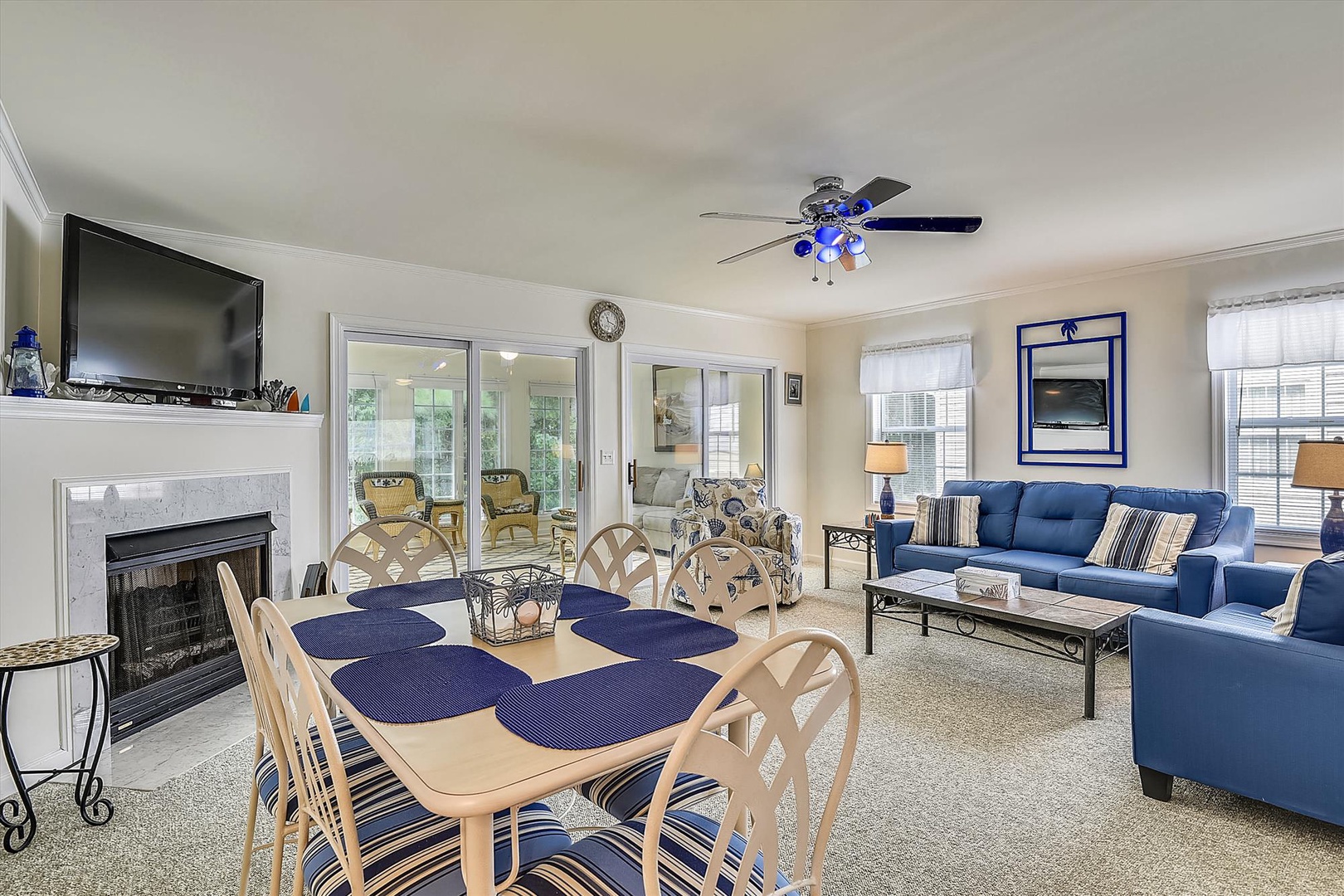 Relax in your bright, open living area with coastal blue accents, a cozy fireplace, and a dining table perfect for gathering over meals.