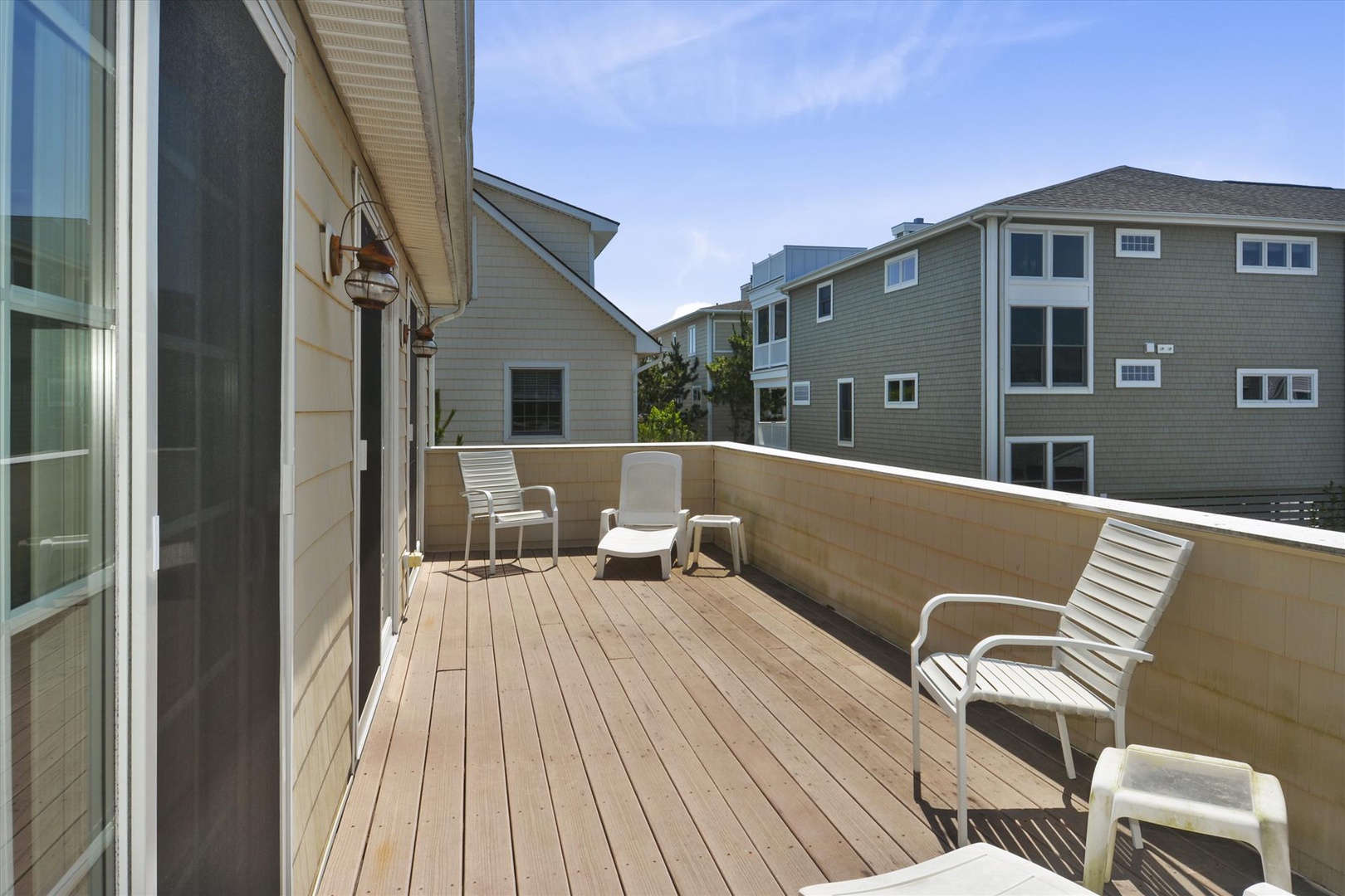 Spacious private deck with comfortable lounge seating, perfect for morning coffee or basking in the coastal sun while surrounded by peaceful neighborhood views.