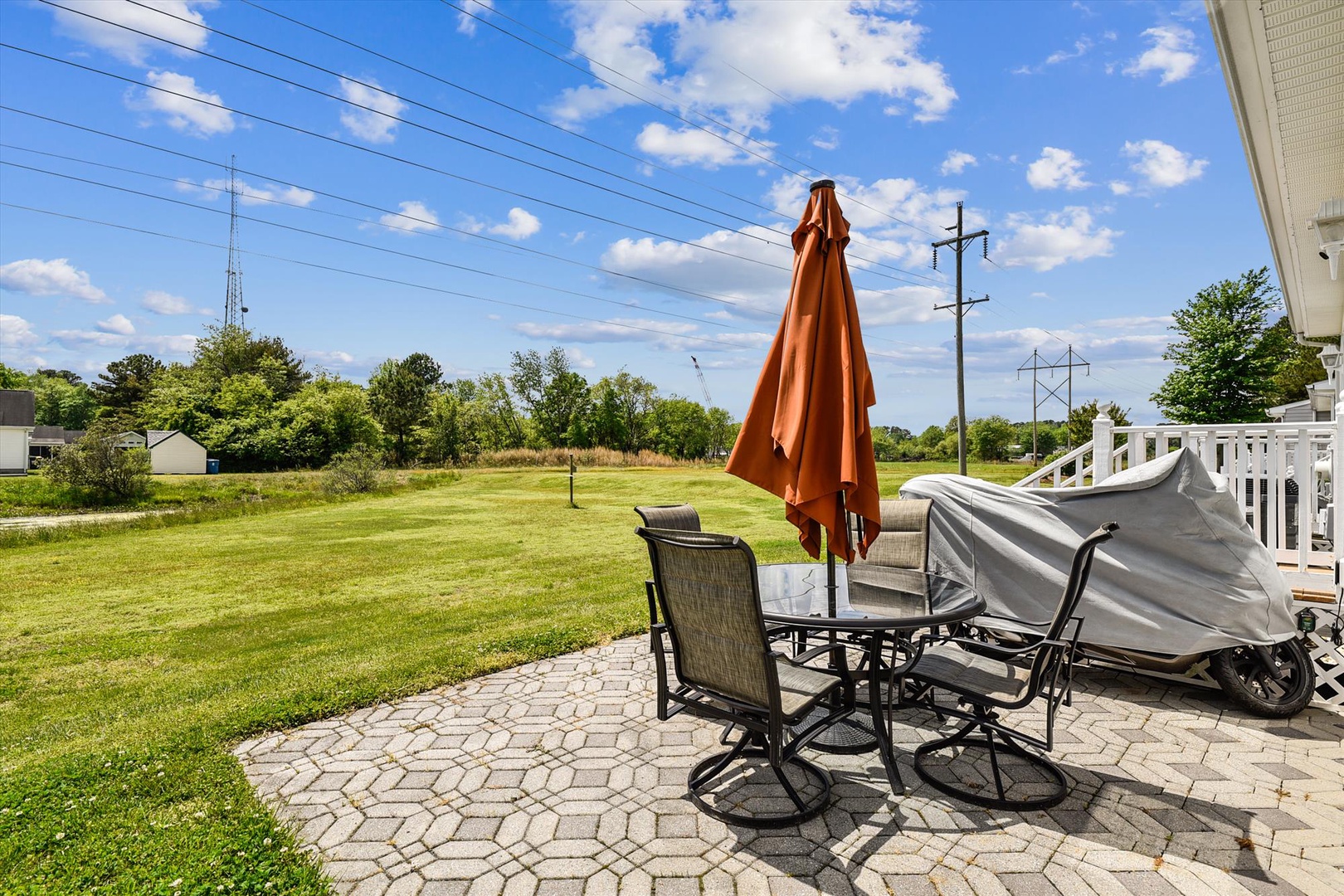 Picture yourself relaxing at this private patio table, shaded by an umbrella, overlooking spacious green lawns stretching toward peaceful countryside views.
