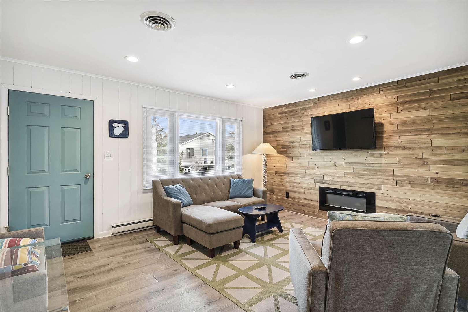 Unwind in your bright, welcoming living room with a stunning reclaimed wood accent wall, flat-screen TV, and cozy fireplace. Sink into plush seating and enjoy natural light streaming through large windows.