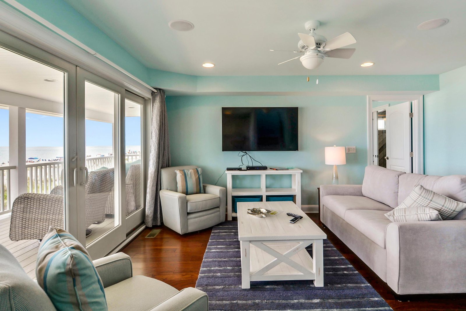 Relax in your bright, coastal living room with serene aqua walls and comfortable seating. Step through the sliding doors to your private balcony overlooking the beach beyond.