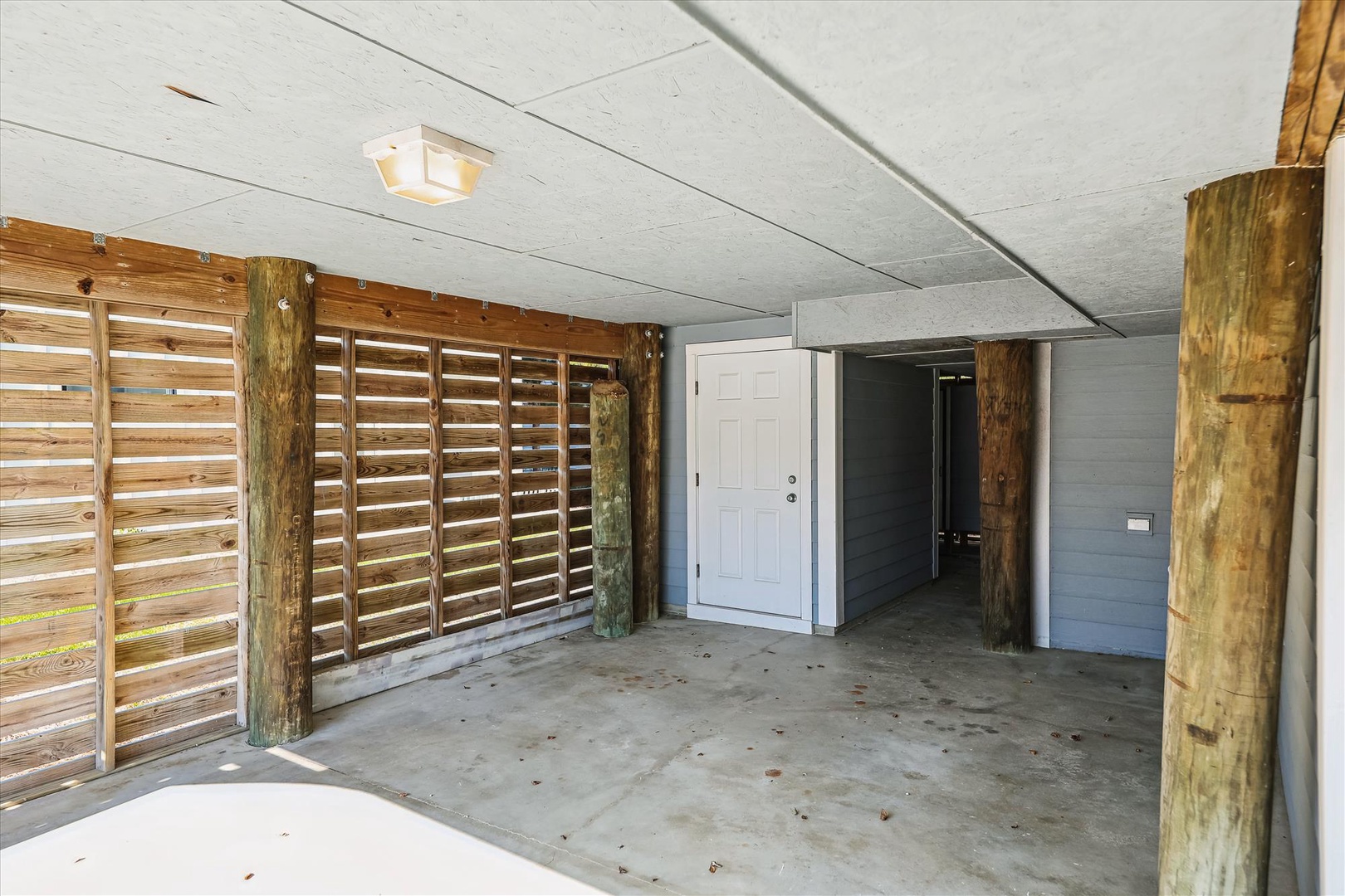 Covered ground-level entry and parking area with rustic wood-post construction, private garage access, and secure entrance to the home above.