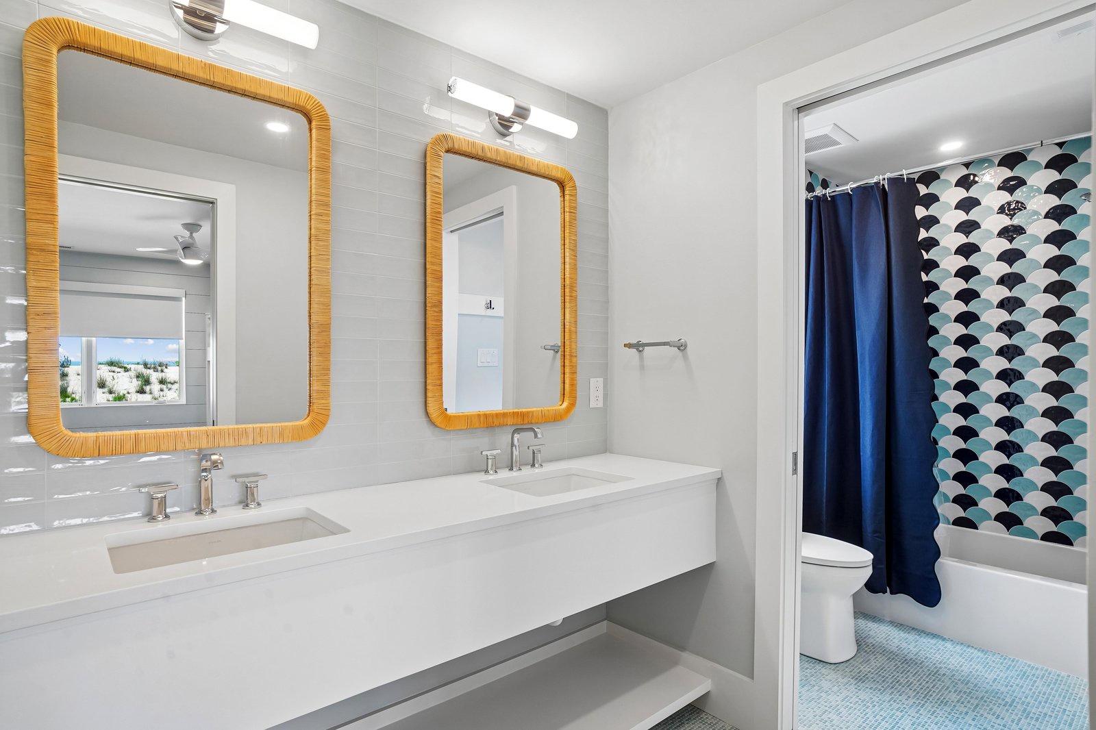 Your bright, modern bathroom features double vanities with stylish mirrors and opens to a spa-like tub and shower area with coastal-inspired tilework.