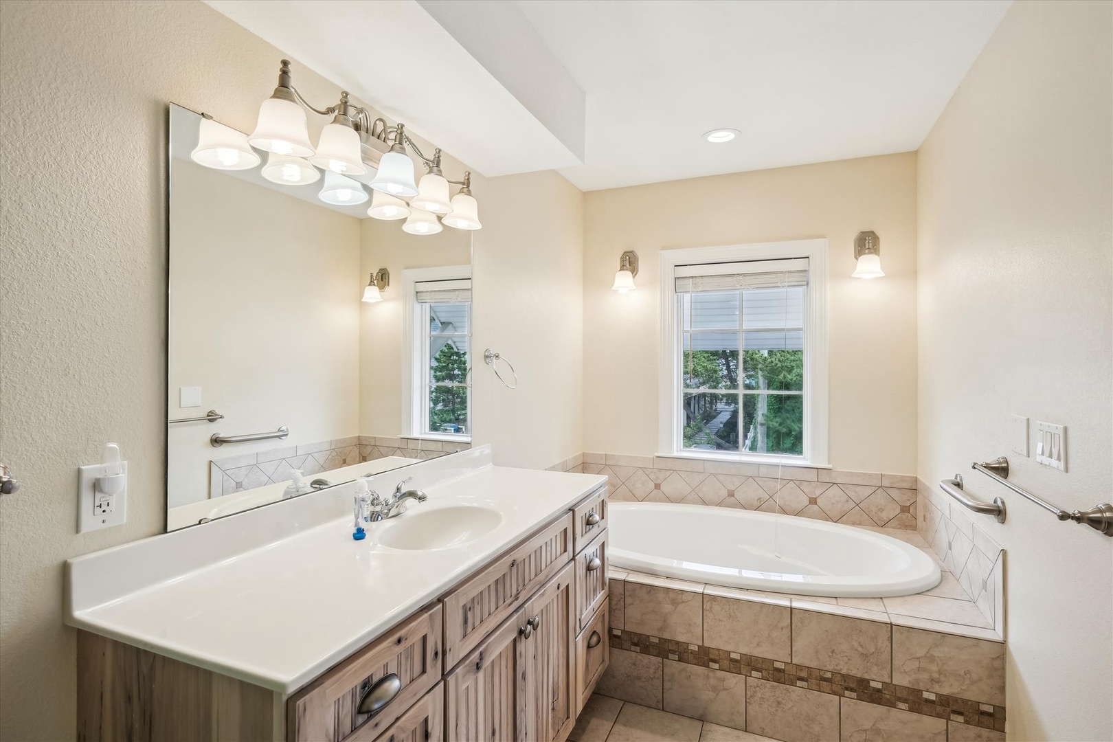 Unwind in your private spa-like bathroom featuring a soaking tub surrounded by elegant tile, bright natural light, and a spacious vanity—perfect for relaxing after a day of adventure.
