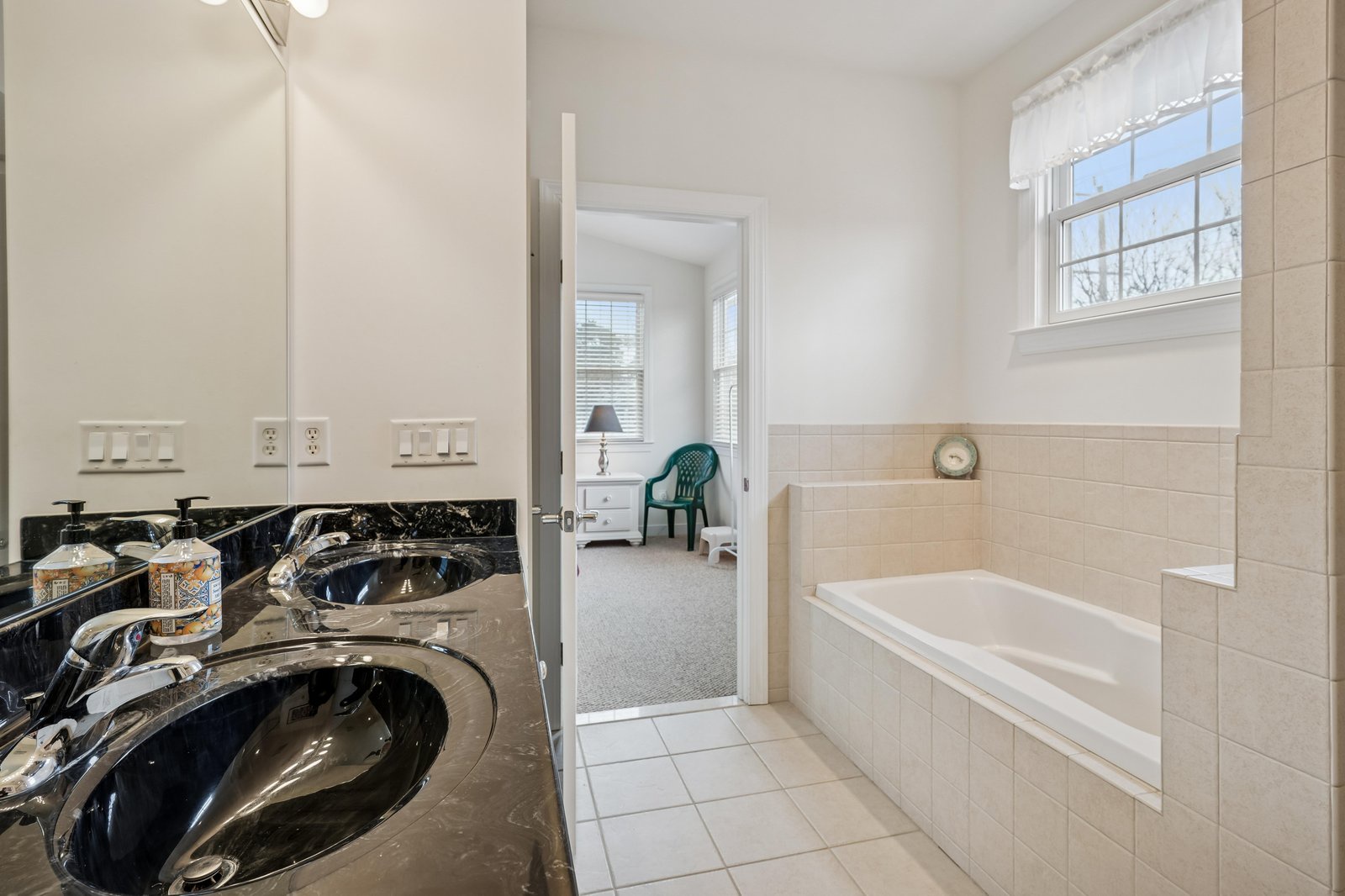 Relax in your spacious bathroom with dual sinks, a soaking tub, and a tranquil view into your private bedroom retreat—your perfect place to unwind.