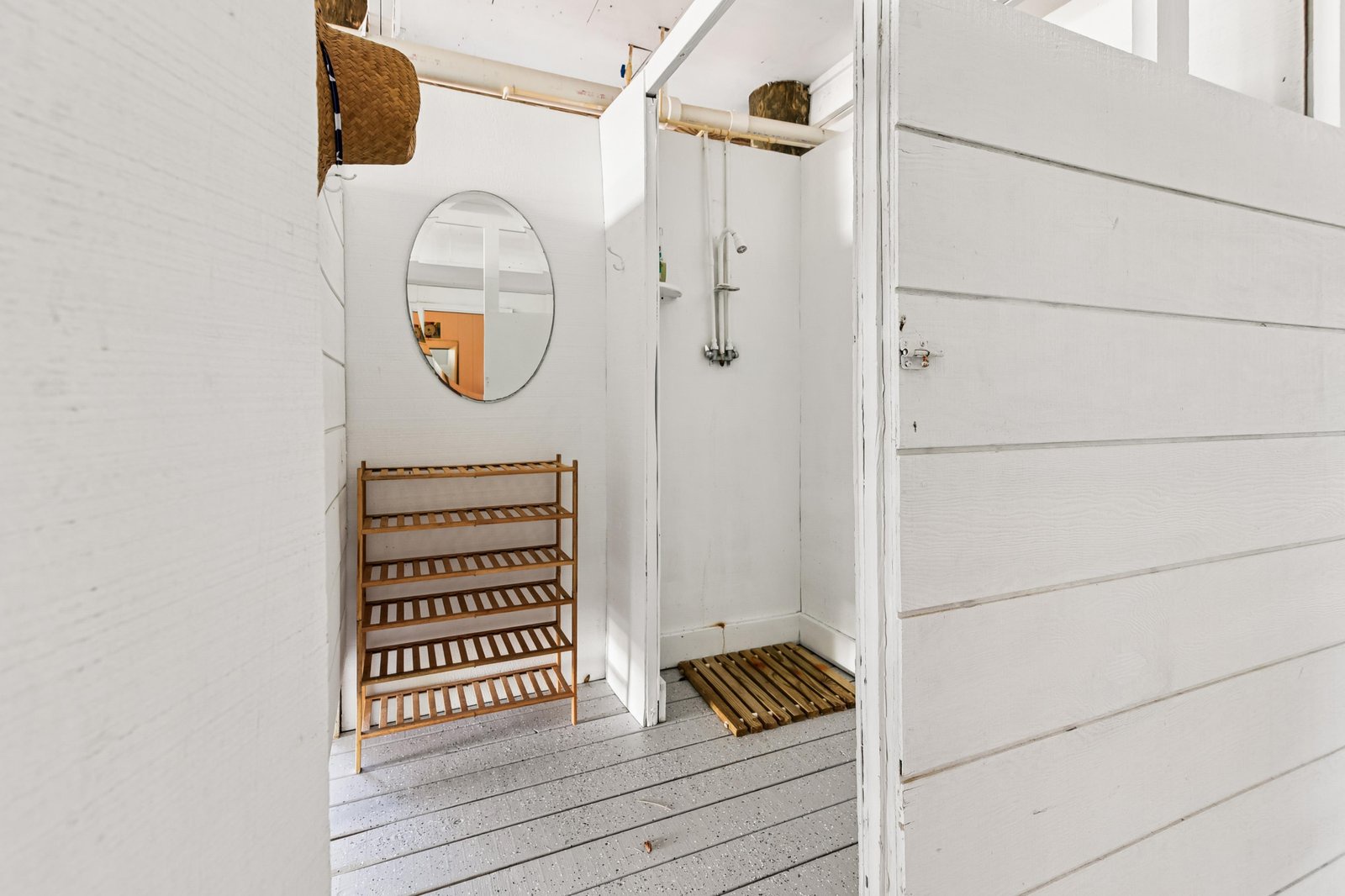 Charming cottage entryway with beamed ceilings, round mirror, and rustic shoe rack—your coastal retreat begins the moment you step inside.