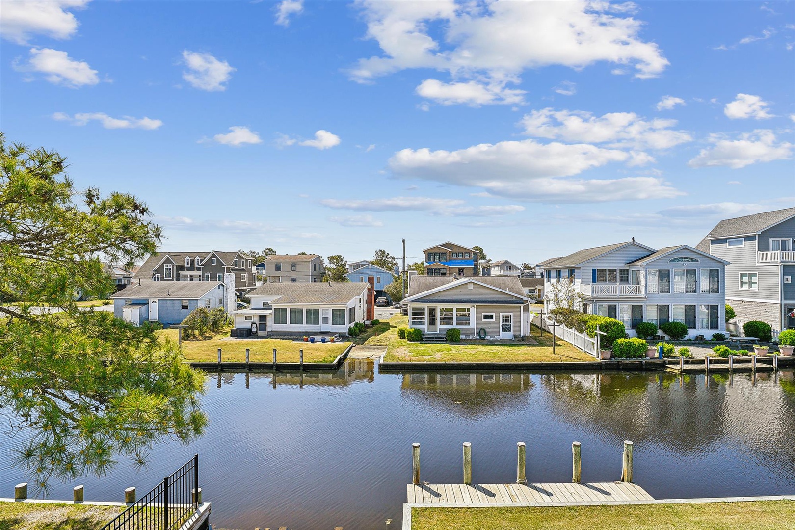 Peaceful waterfront neighborhood with direct canal access and private dock, surrounded by coastal homes beneath expansive skies.