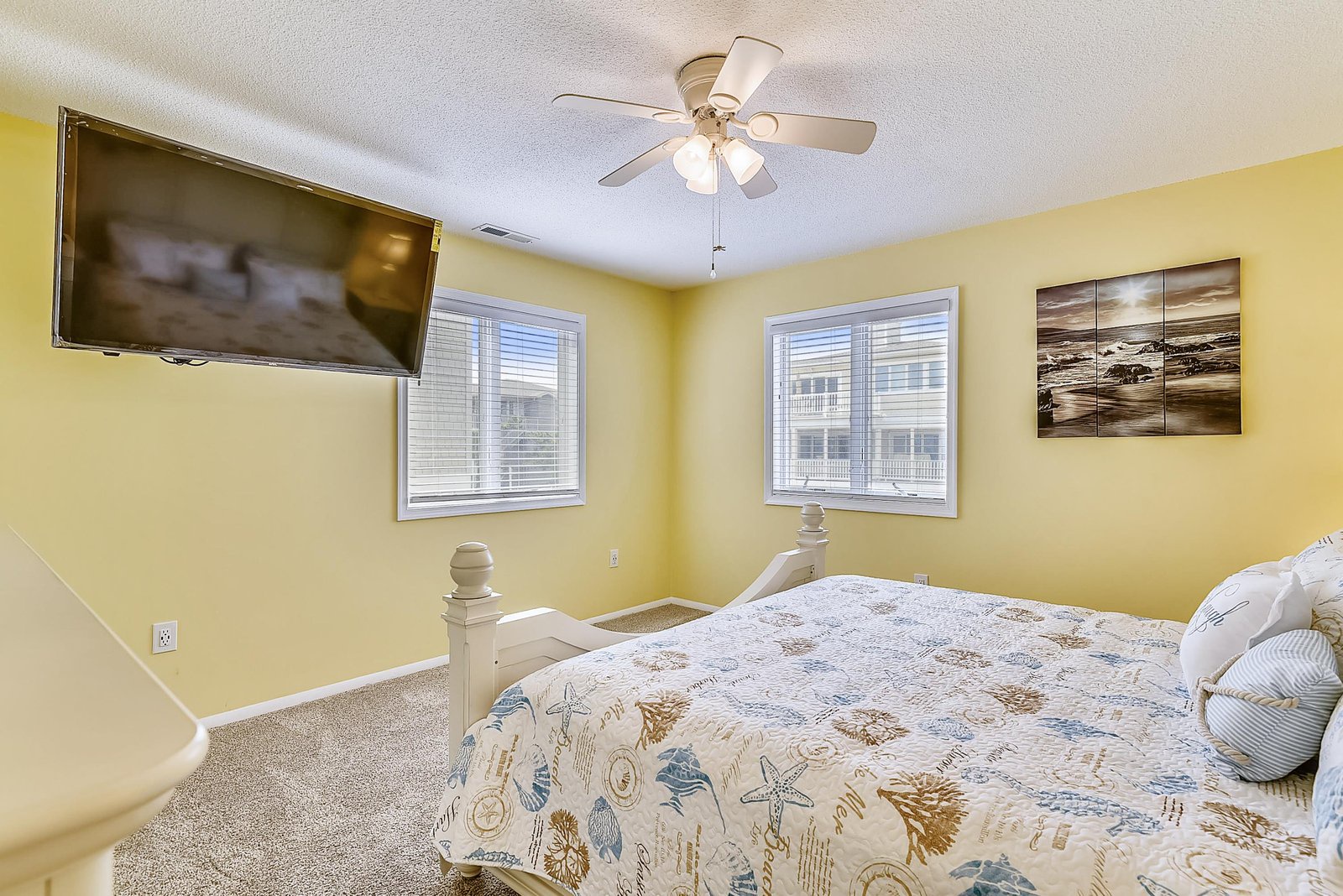 Your cheerful bedroom awaits with a plush bed, ceiling fan, flat-screen TV, and plenty of natural light—perfect for unwinding after a day of coastal adventures.