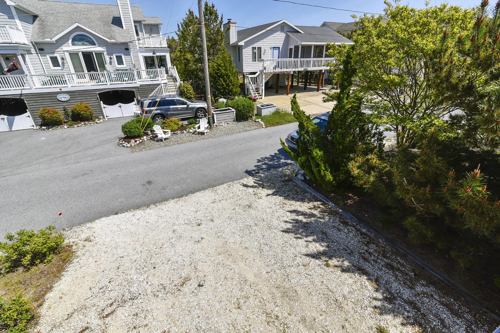 Elevated beach homes nestled in a quiet coastal neighborhood surrounded by mature trees, with convenient parking and easy access to local amenities.