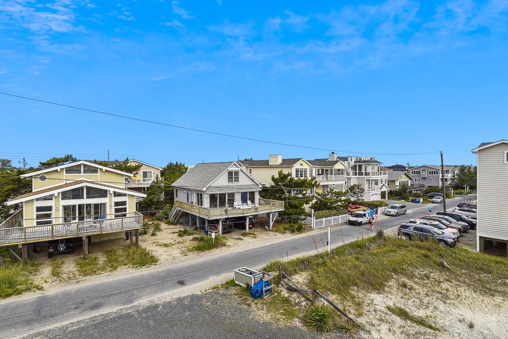 Charming beach community featuring coastal rental homes along a quiet sandy street, offering an authentic seaside neighborhood atmosphere.