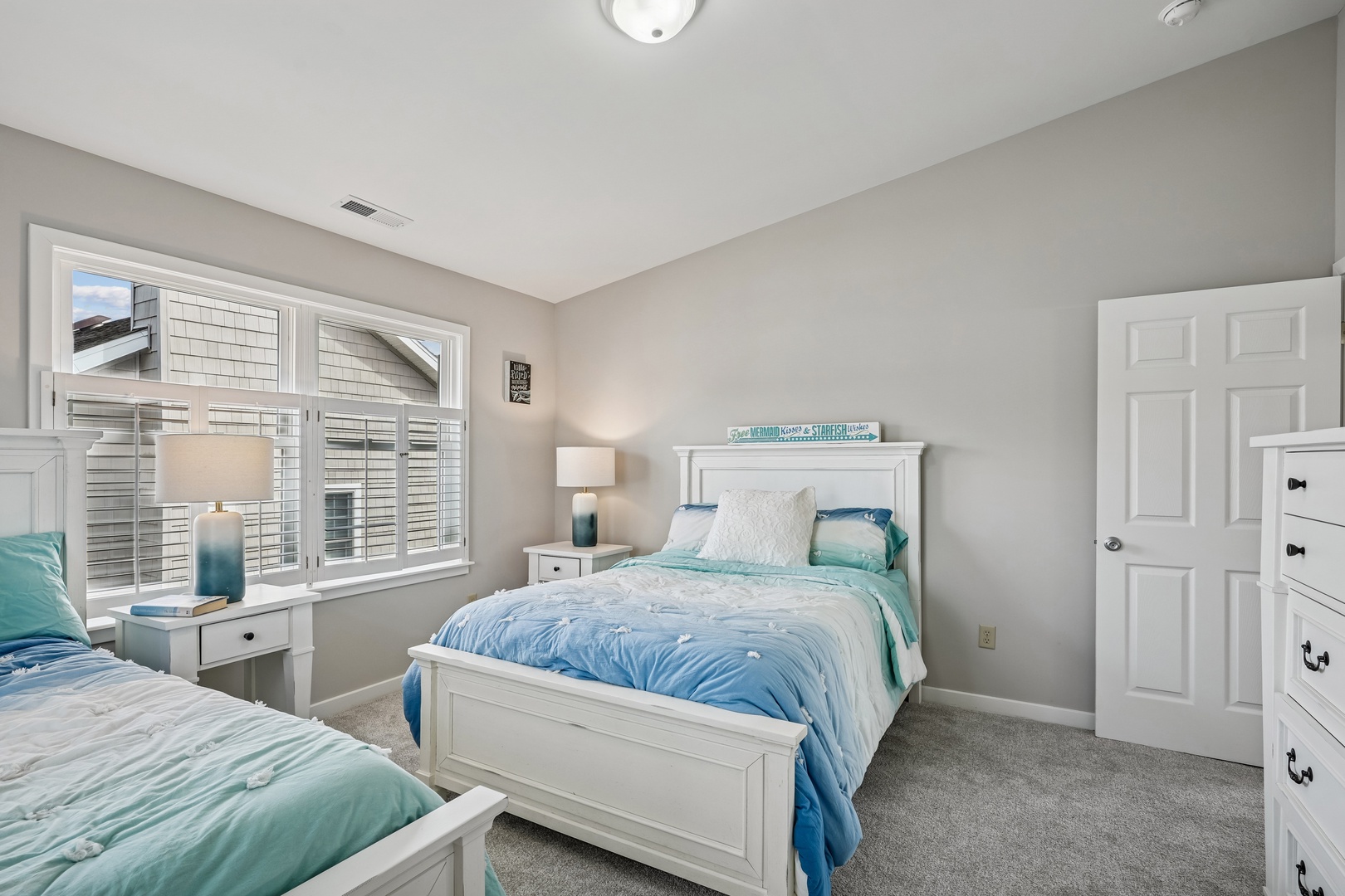 Sink into coastal comfort in your serene bedroom featuring twin beds with ocean-inspired linens and calming tones.