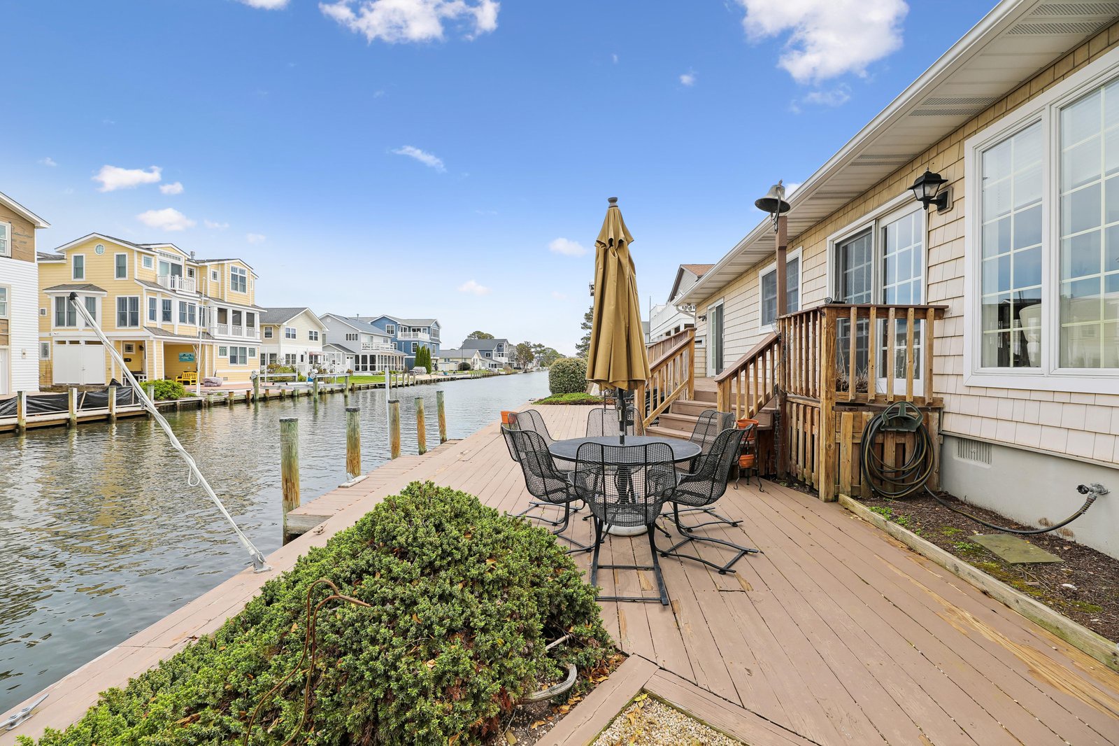 Waterfront property featuring a private deck with outdoor furniture, canal access with dock, and views of neighboring homes and marina. Located in a peaceful residential waterway community.