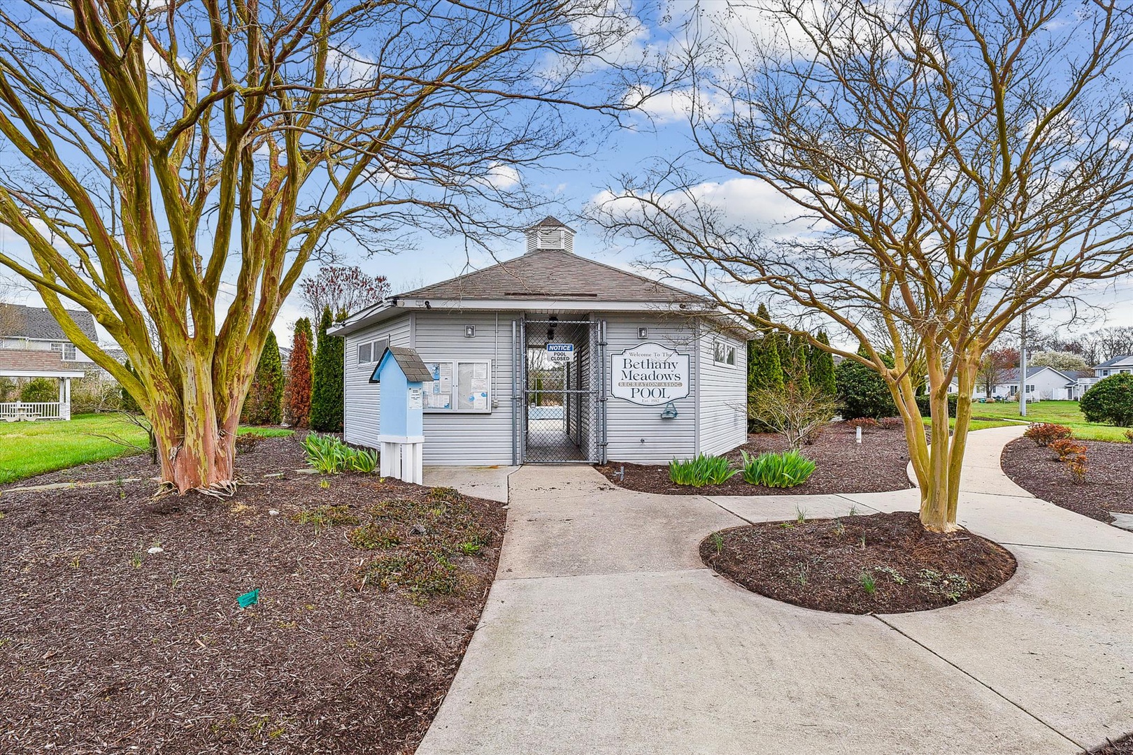 The property entrance at Bethany Meadows welcomes visitors with landscaped grounds and a charming gatekeeper building flanked by mature trees.
