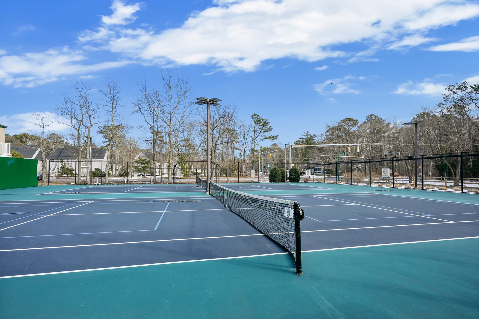 Well-maintained tennis courts with professional nets and clear court markings in a peaceful residential setting.