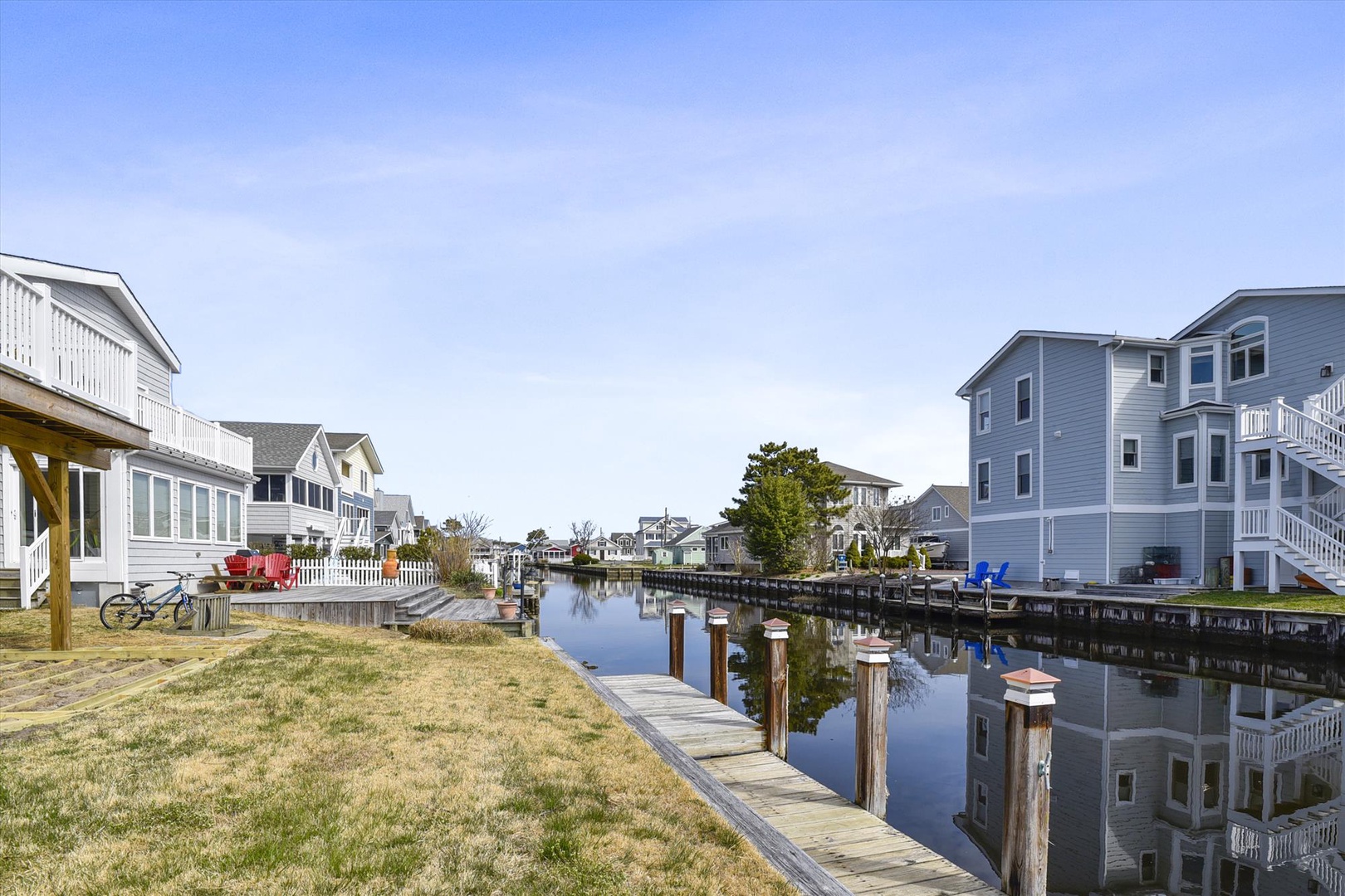 Peaceful waterfront neighborhood with private docks and charming coastal homes lining a serene canal under clear blue skies.