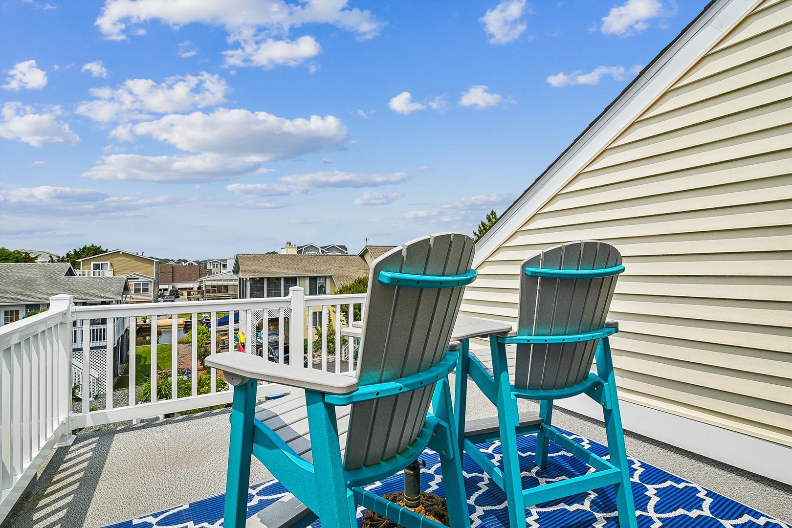 This private balcony showcases a peaceful neighborhood setting with comfortable Adirondack chairs—ideal for morning coffee or evening relaxation under open skies.