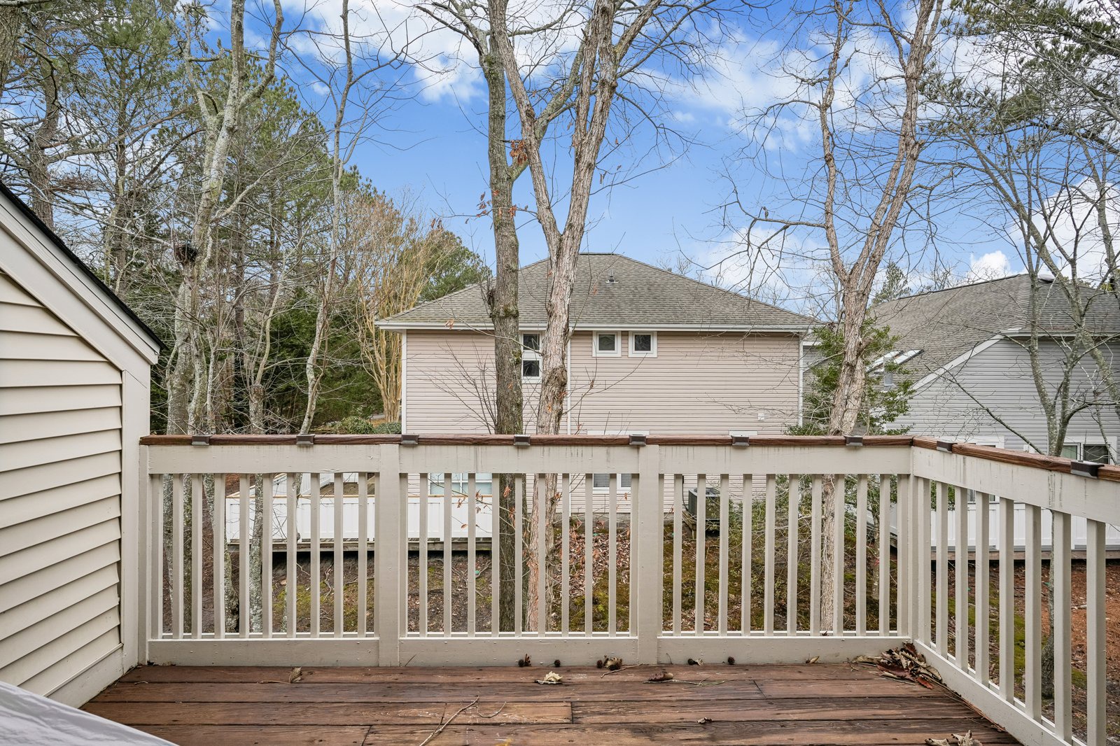 Private deck overlooking peaceful residential neighborhood with mature trees and neighboring homes.
