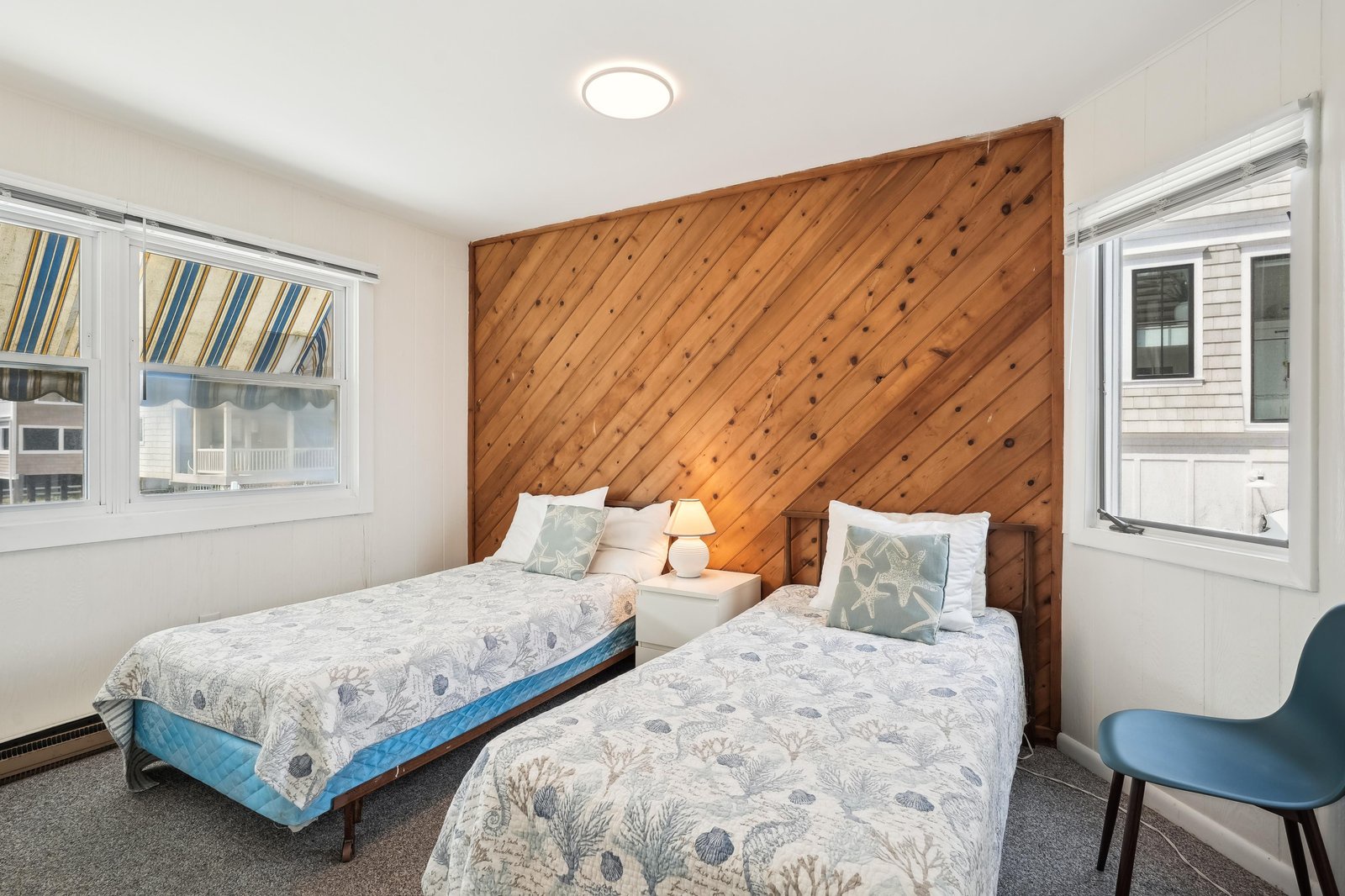 Your cozy coastal retreat awaits with two plush beds, warm wood accents, and soft natural light—perfect for unwinding after a day of seaside adventures.