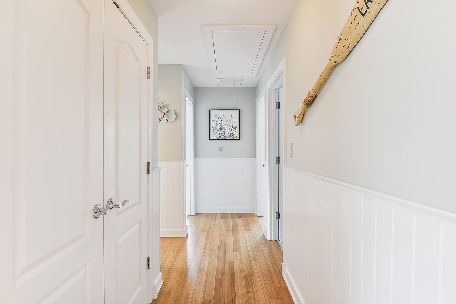 This bright hallway connects the home with coastal charm, from the warm wood floors to the decorative paddle adding a nautical touch overhead.