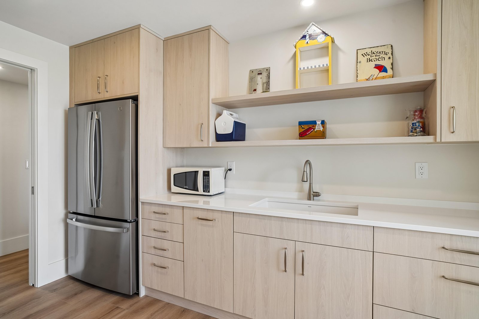 Your kitchen awaits with sleek stainless-steel appliances, bright countertops, and open shelving for a relaxed, beach-cottage vibe.