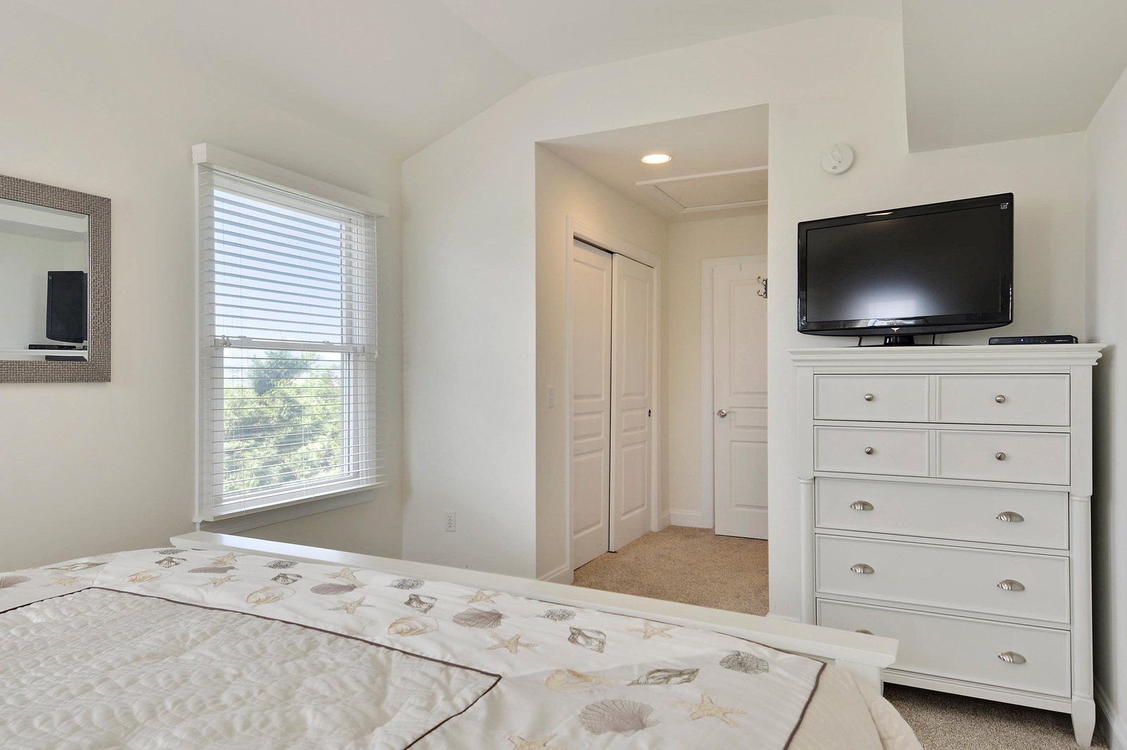 Your bright, coastal-inspired bedroom features a comfortable queen bed, flat-screen TV, and a large window that fills the space with natural light—perfect for unwinding after a day at the beach.