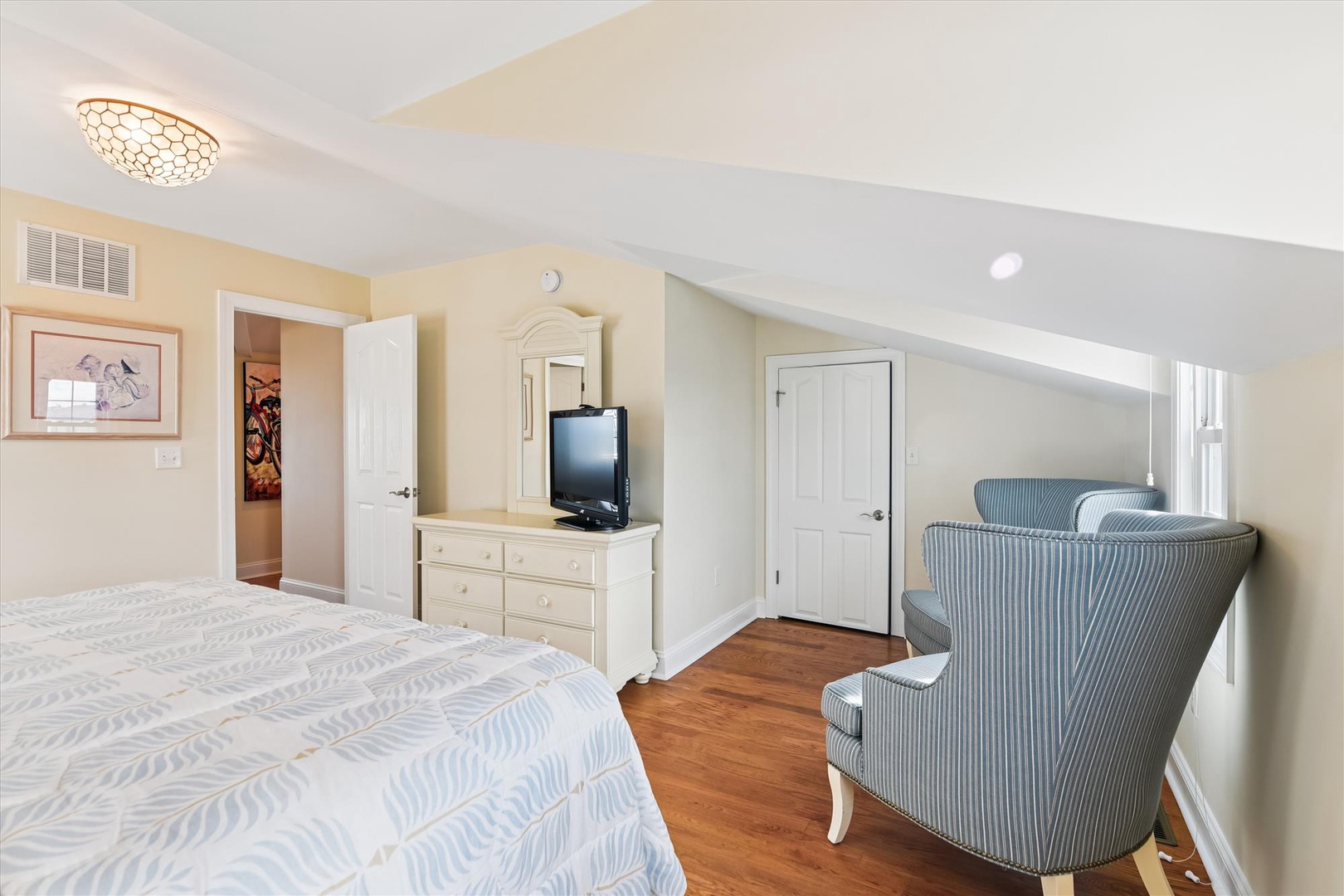 Relax in your spacious bedroom with plush bedding, cozy seating, and warm wood floors. Unwind under elegant lighting after a day of exploring nearby attractions.