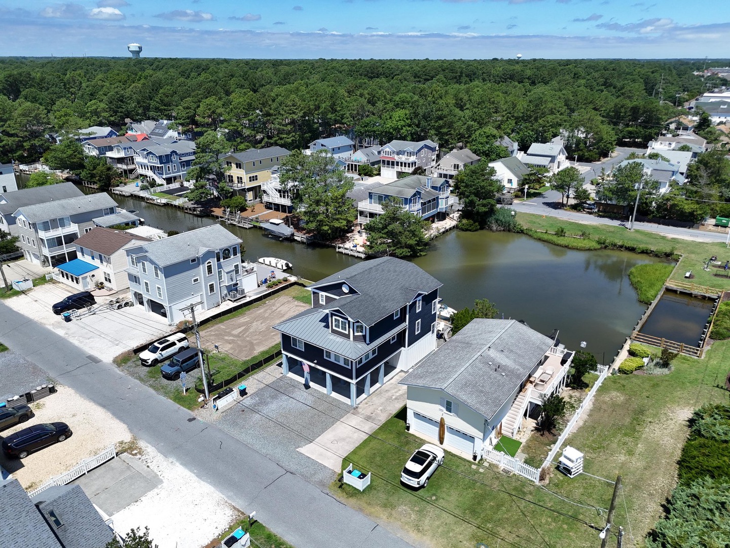Aerial view of a waterfront residential neighborhood with canal access homes surrounded by lush forest and natural landscapes.