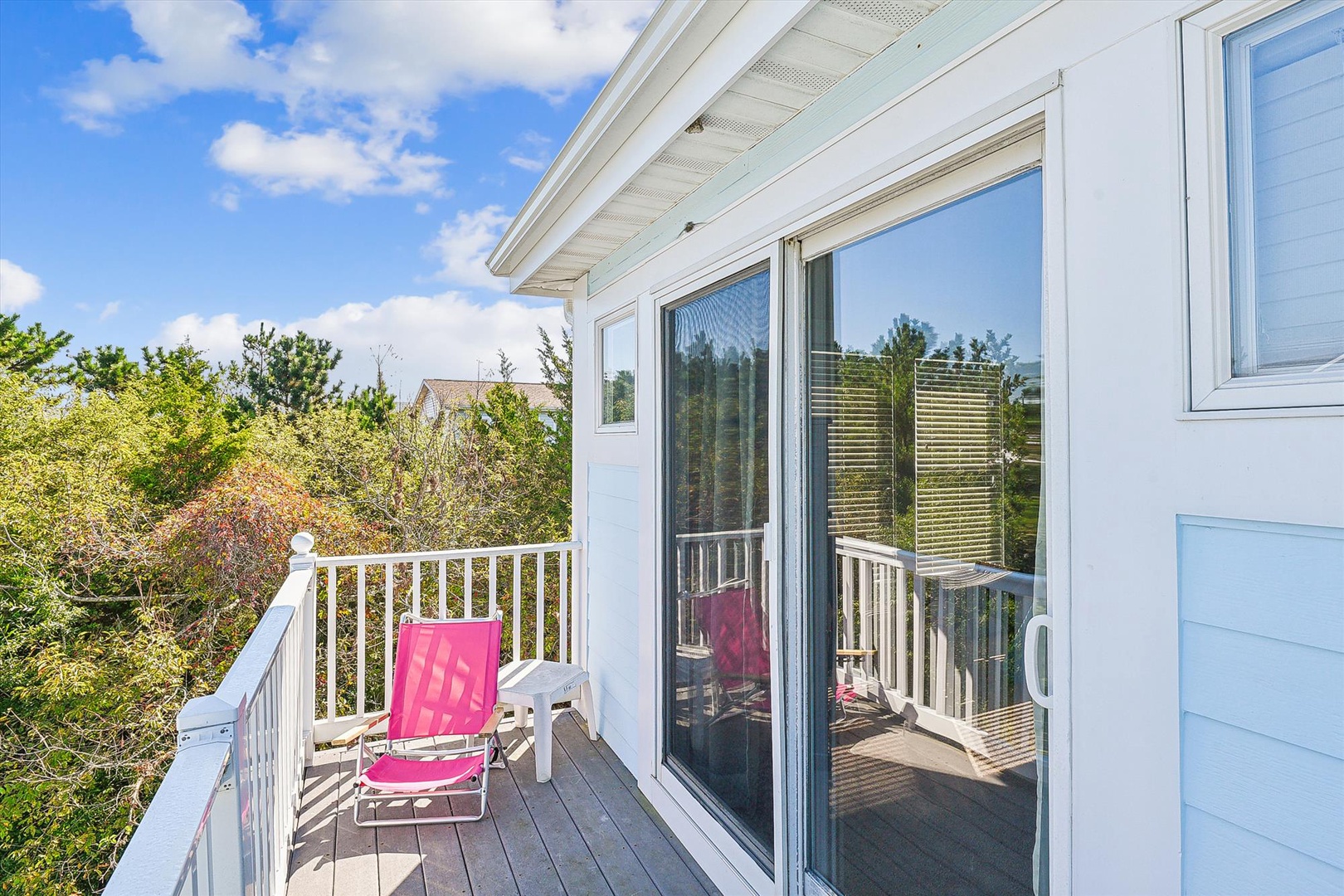 Bright balcony with comfy seating overlooking lush greenery. Step outside for fresh air and peaceful moments under blue skies.