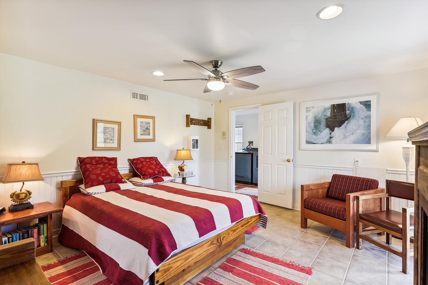 Unwind in your spacious bedroom, where a plush bed with bold red accents awaits beneath a gentle ceiling fan. Cozy seating and warm lighting create the perfect retreat after a day of exploring.
