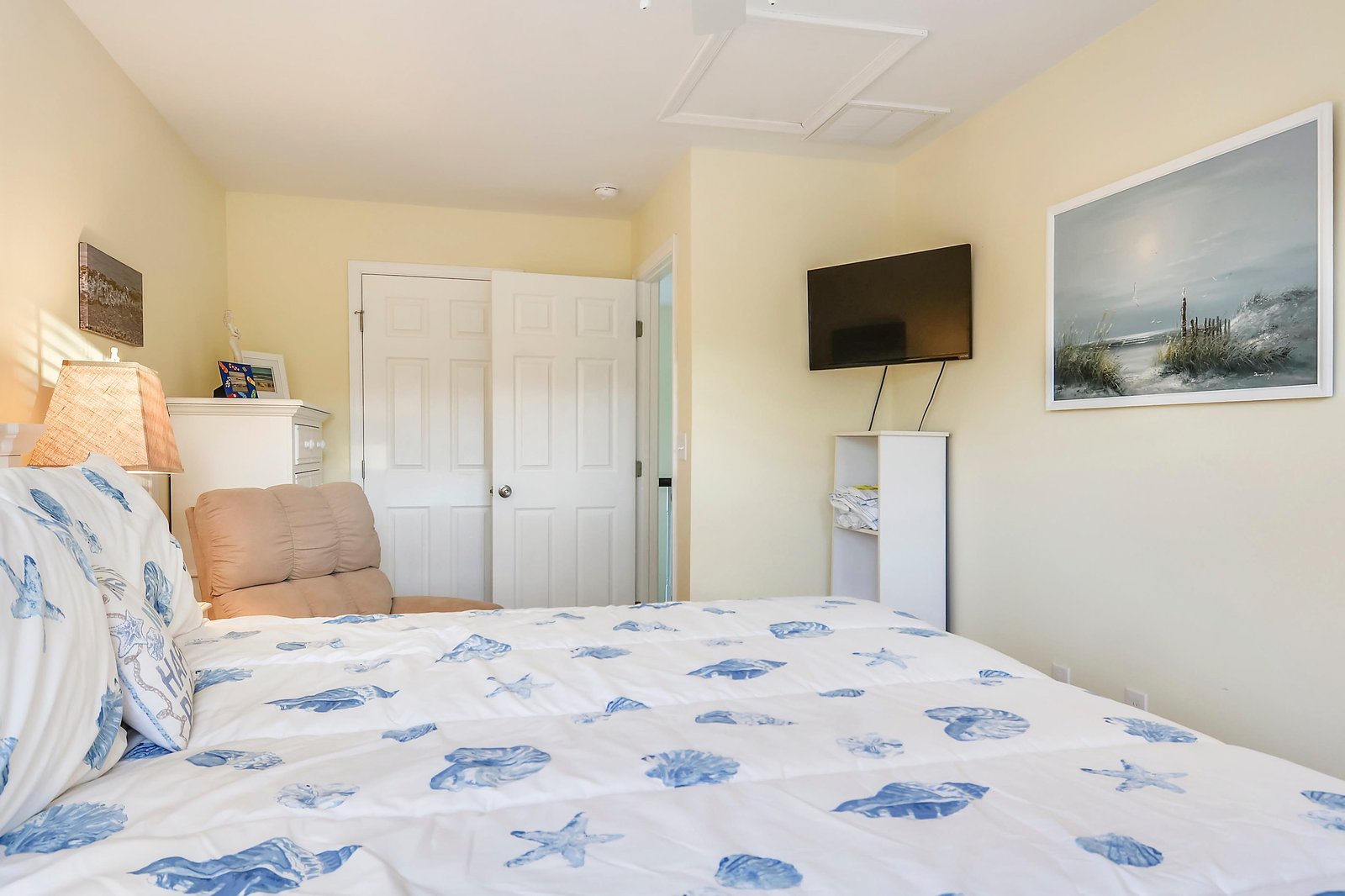 Drift off beneath soft coastal linens and wake refreshed in your serene retreat, where cheerful yellow walls and beach-inspired artwork welcome you to unwind after each day's adventure.