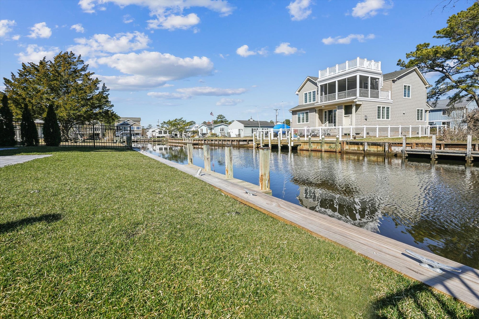 Waterfront property with private dock access, expansive lawn, and serene canal views, located in a peaceful residential neighborhood surrounded by natural beauty.