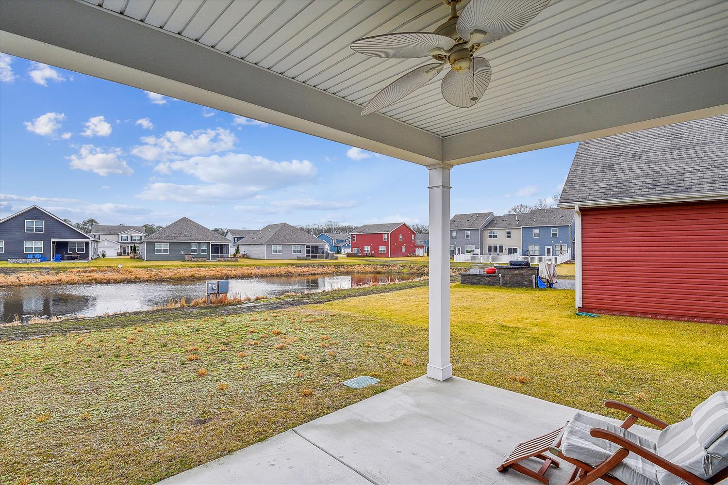 Covered patio overlooking a peaceful residential pond in a quiet neighborhood setting with spacious backyard area.