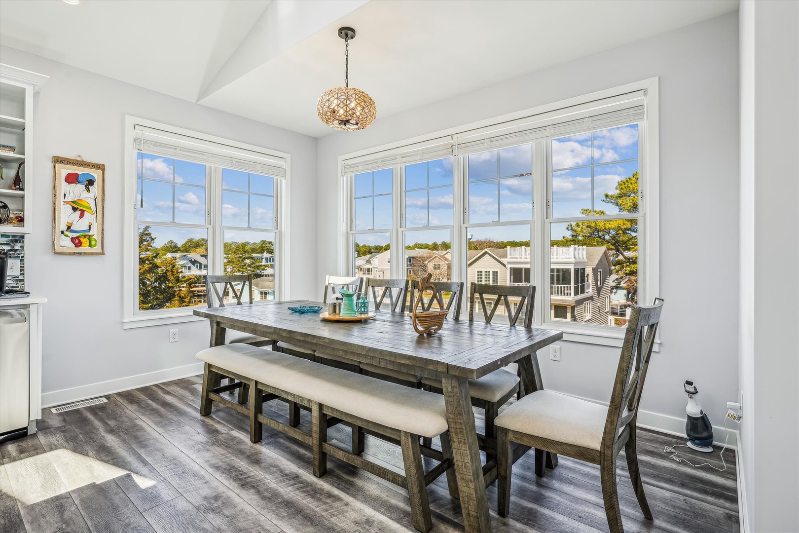 Gather around this spacious dining table bathed in natural light, with room for everyone to share meals and make memories together beneath a charming woven pendant light.